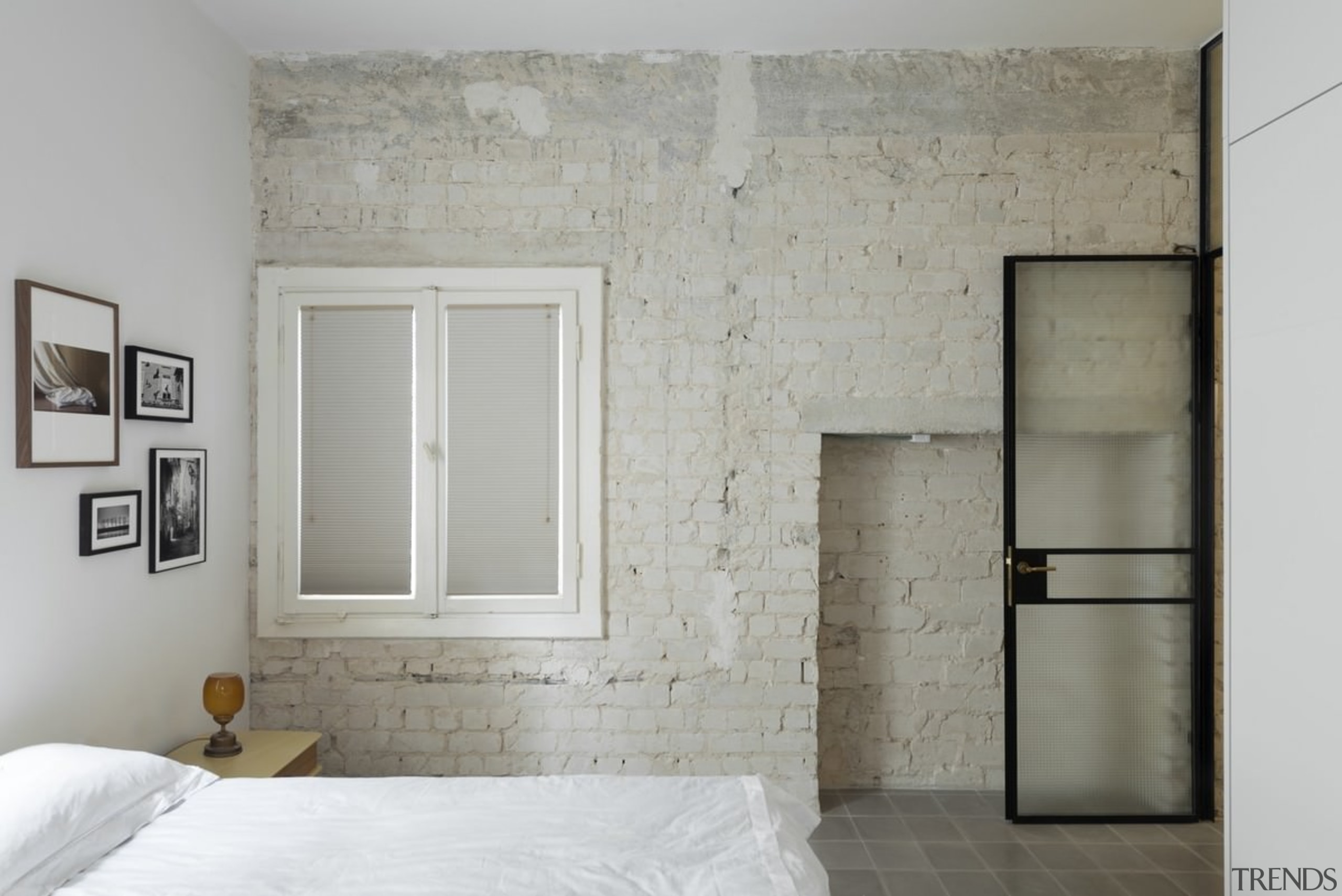 The original brick wall in this bedroom adds bed frame, ceiling, door, floor, home, interior design, plaster, room, wall, window, gray