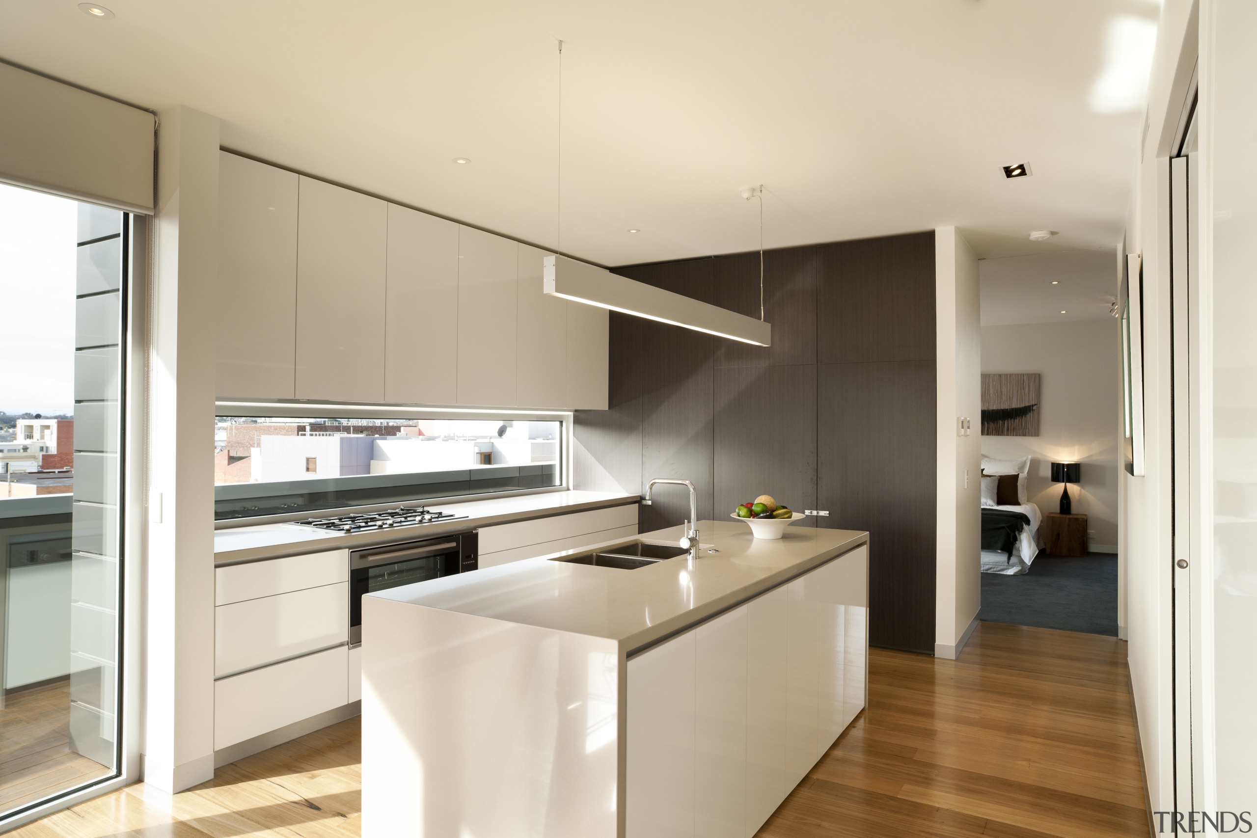 This galley-style kitchen features a large island with architecture, cabinetry, countertop, cuisine classique, interior design, kitchen, real estate, white