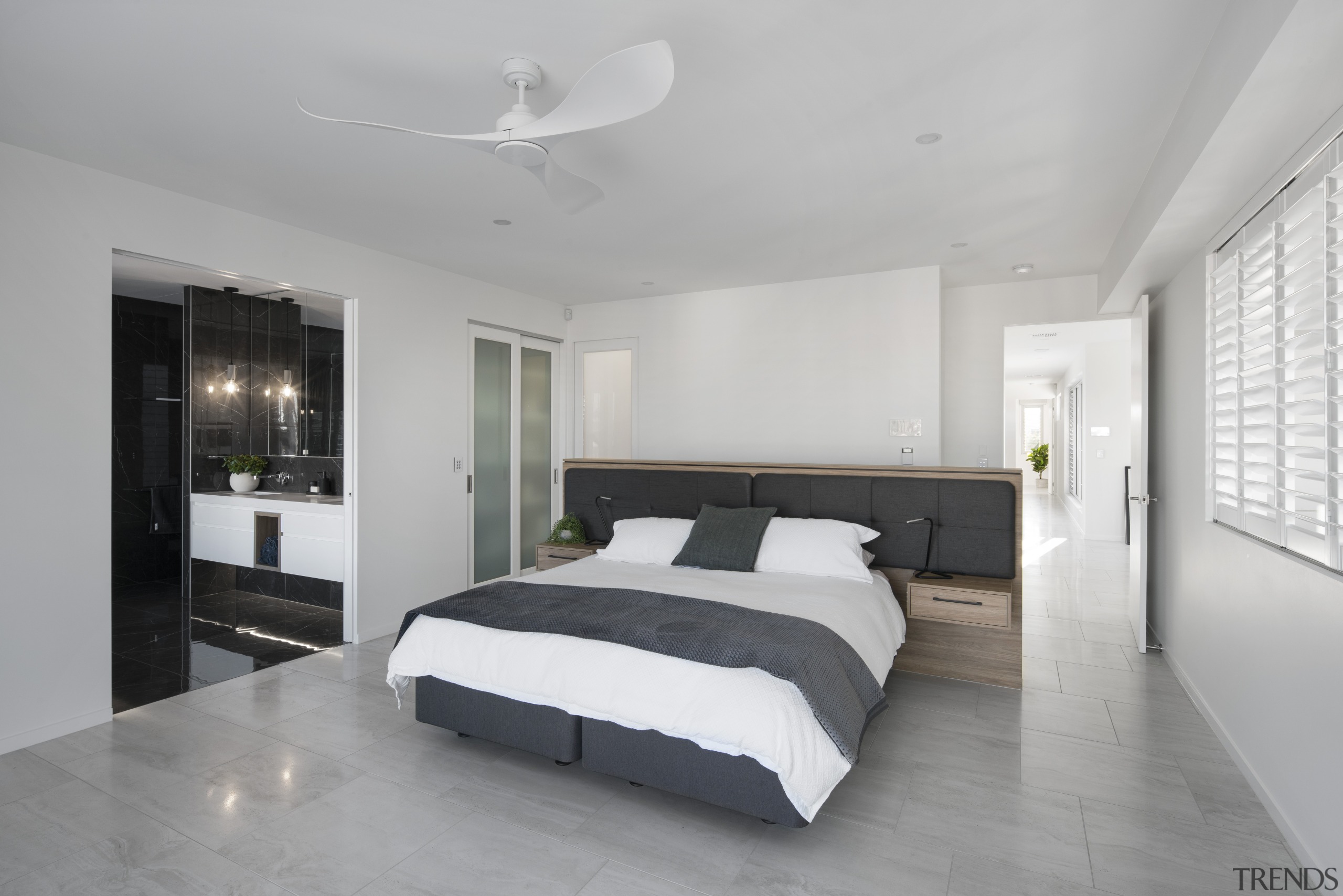 In this bathroom by Elenel Design, the white architecture, bed, bed frame, bed sheet, bedding, bedroom, black-and-white, boutique hotel, building, ceiling, comfort, daylighting, floor, flooring, furniture, hardwood, home, house, interior design, mattress, mattress pad, nightstand, property, real estate, room, suite, tile, wall, white, gray