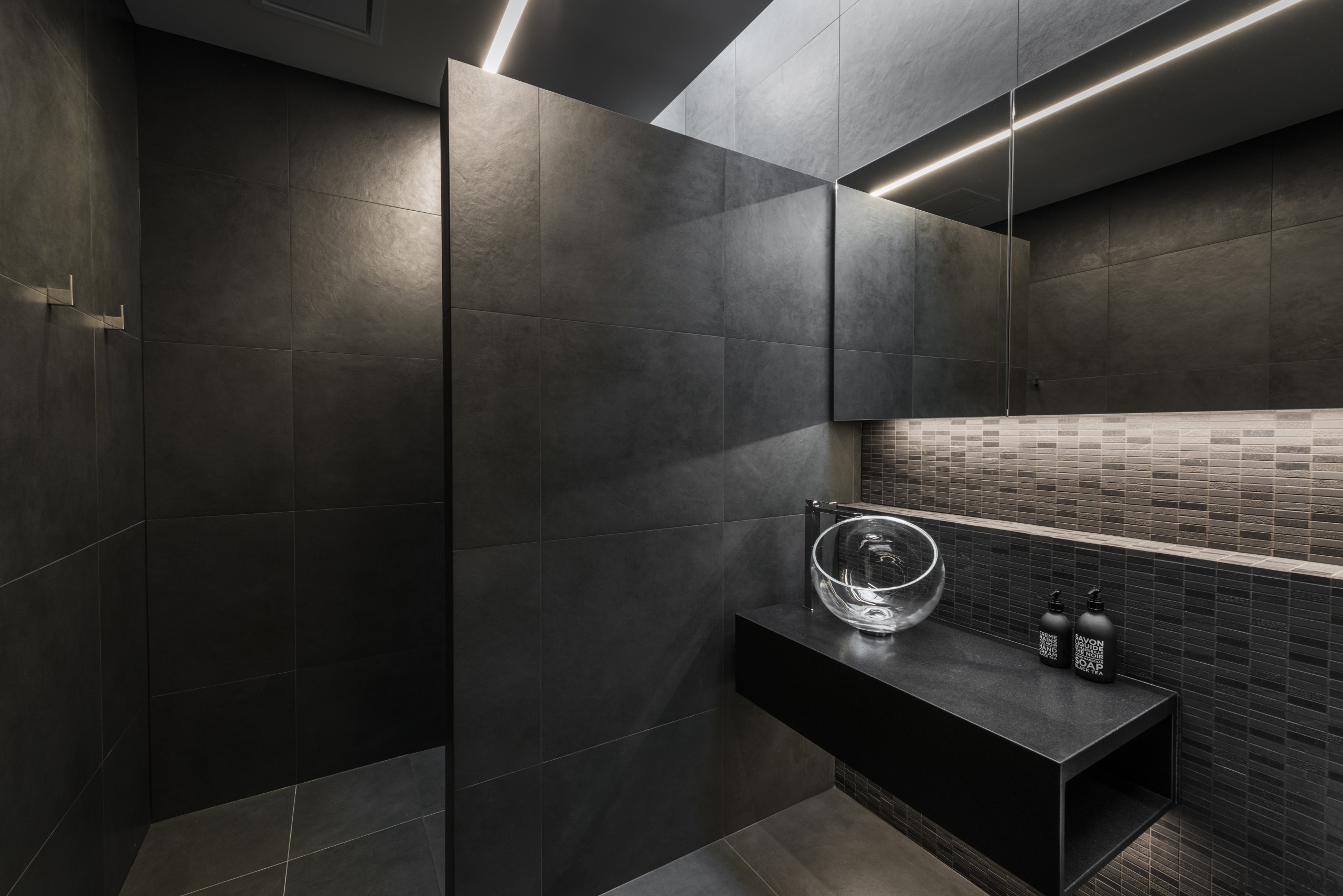 Designer Davinia Sutton created a moody space with architecture, bathroom, building, floor, flooring, house, interior design, material property, plumbing fixture, property, room, tile, wall, black