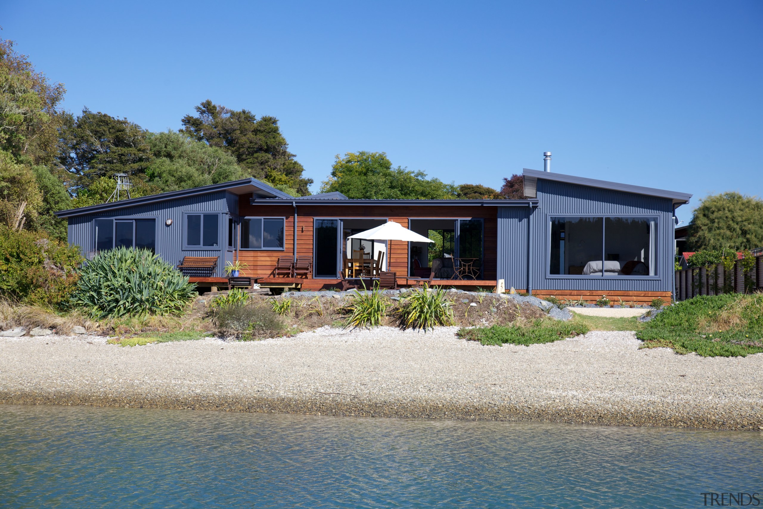 Nestled among the trees on the shoreline at cottage, estate, facade, home, house, property, real estate, sky, villa, water, teal