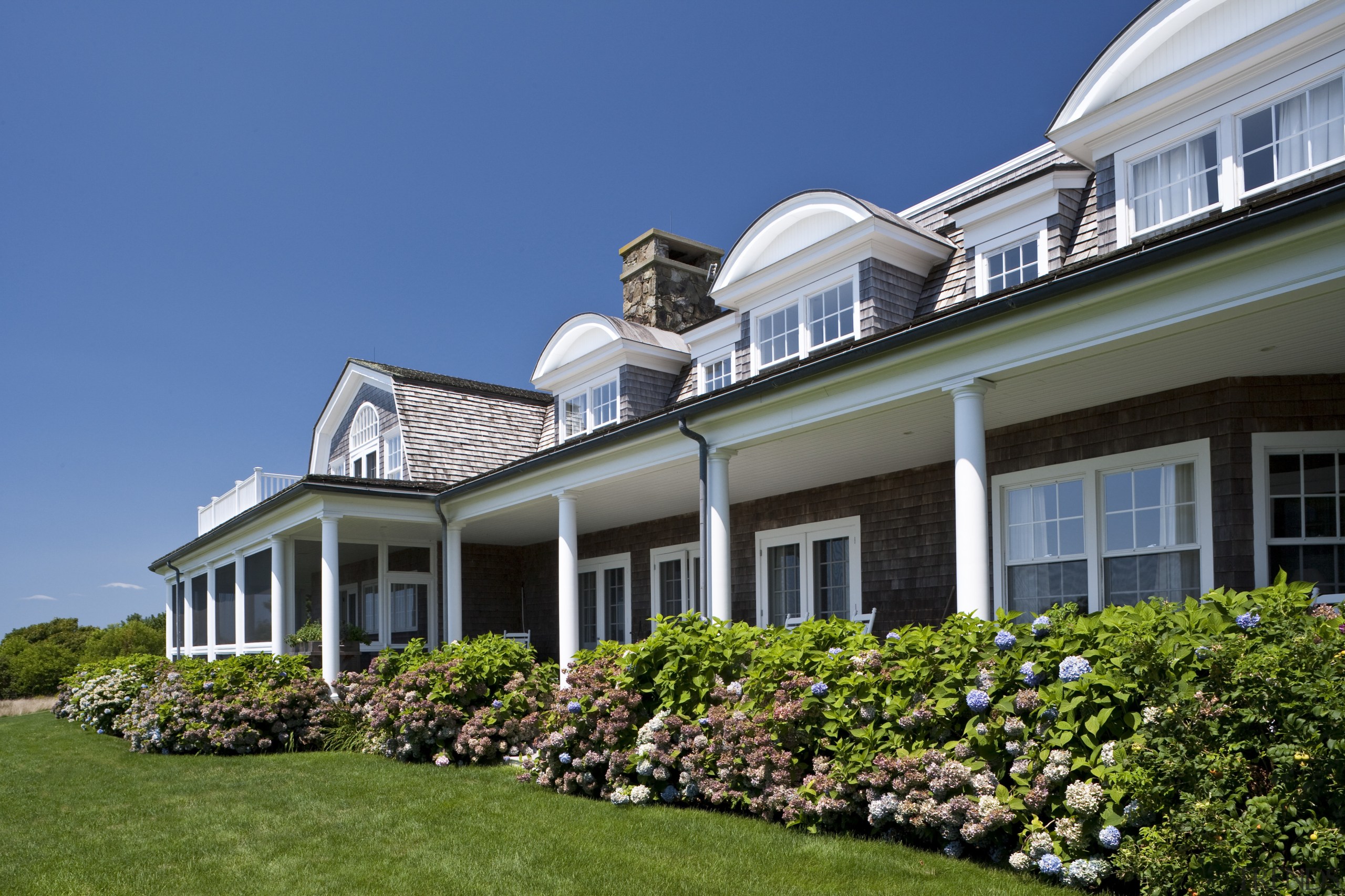 Exterior view of a New-England styled vacation home. cottage, estate, facade, farmhouse, grass, home, house, landscaping, lawn, mansion, property, real estate, residential area, roof, siding, sky, villa, window, blue