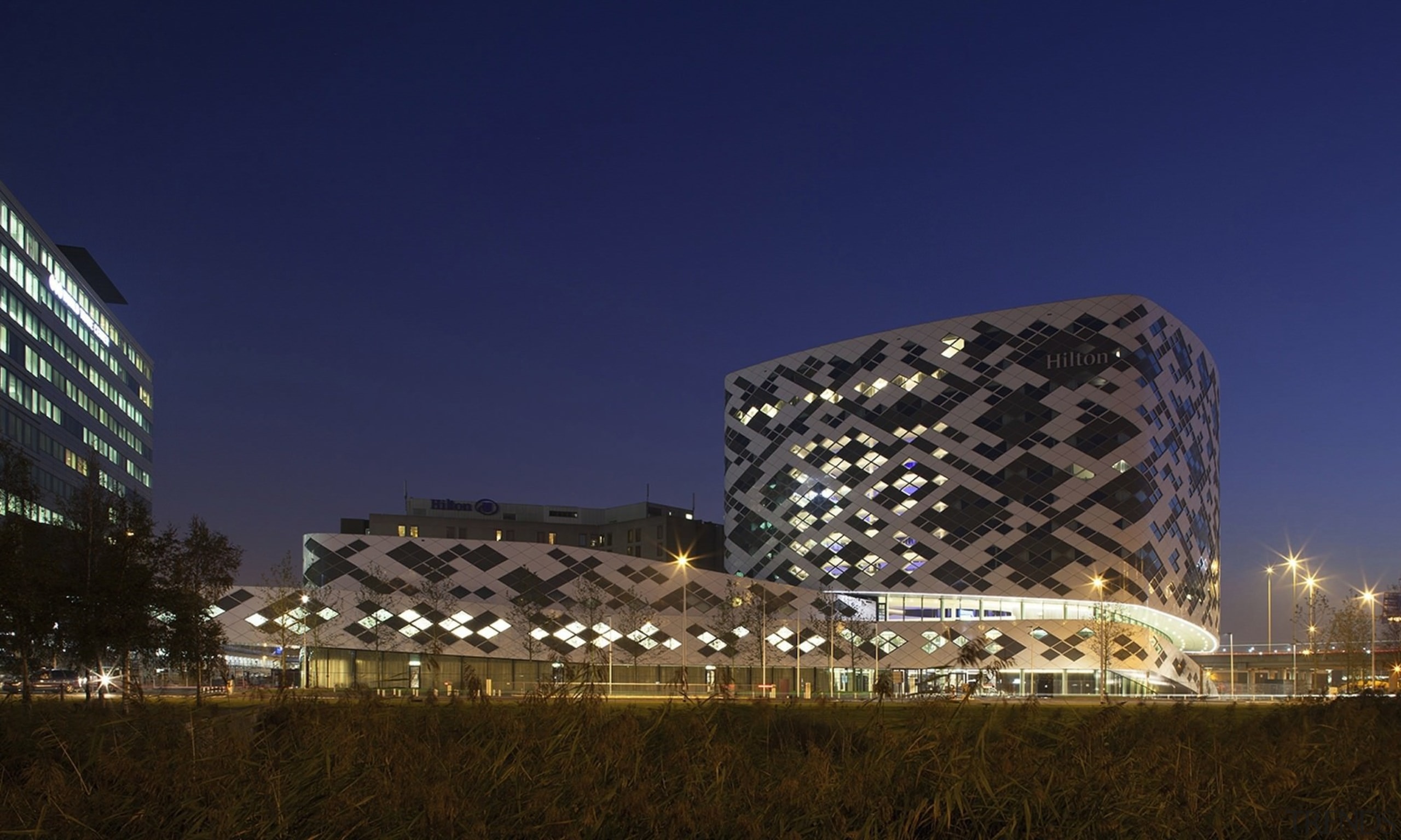 A unique facade covers the building - A architecture, building, city, corporate headquarters, landmark, metropolis, night, sky, structure, tourist attraction, tower block, blue, brown
