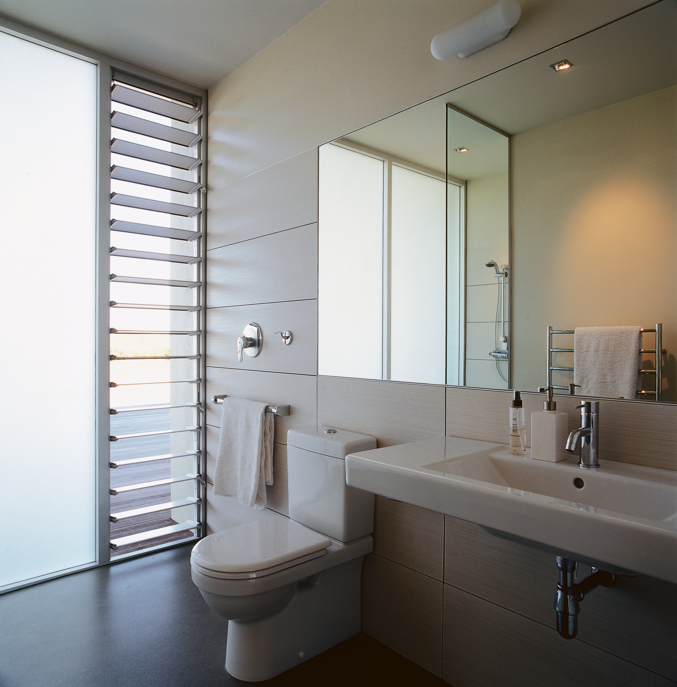 A view of this clean streamlined bathroom featuring architecture, bathroom, bathroom accessory, bathroom cabinet, daylighting, home, interior design, plumbing fixture, room, sink, window, white, gray