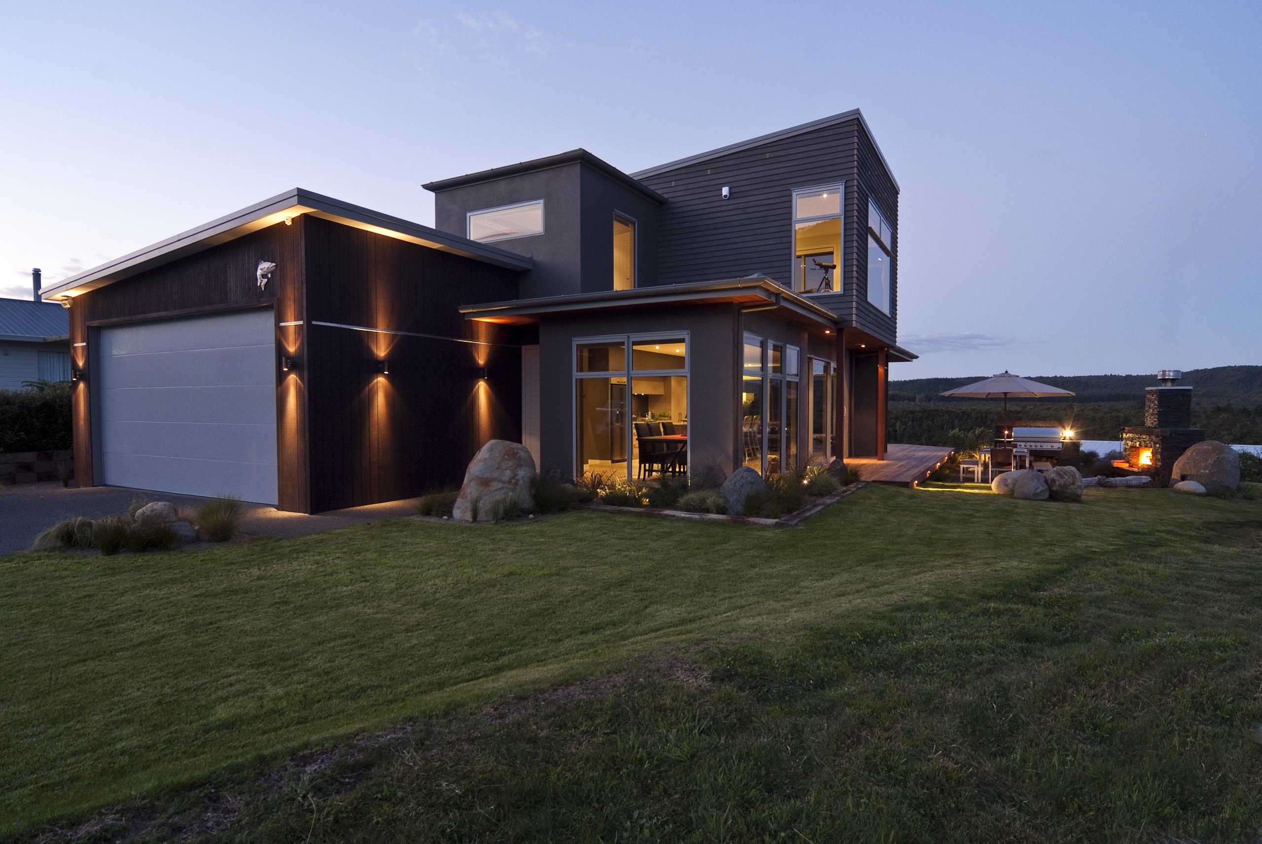 Evening view of this modern home overlooks the cottage, facade, home, house, property, real estate, roof, siding, black, teal