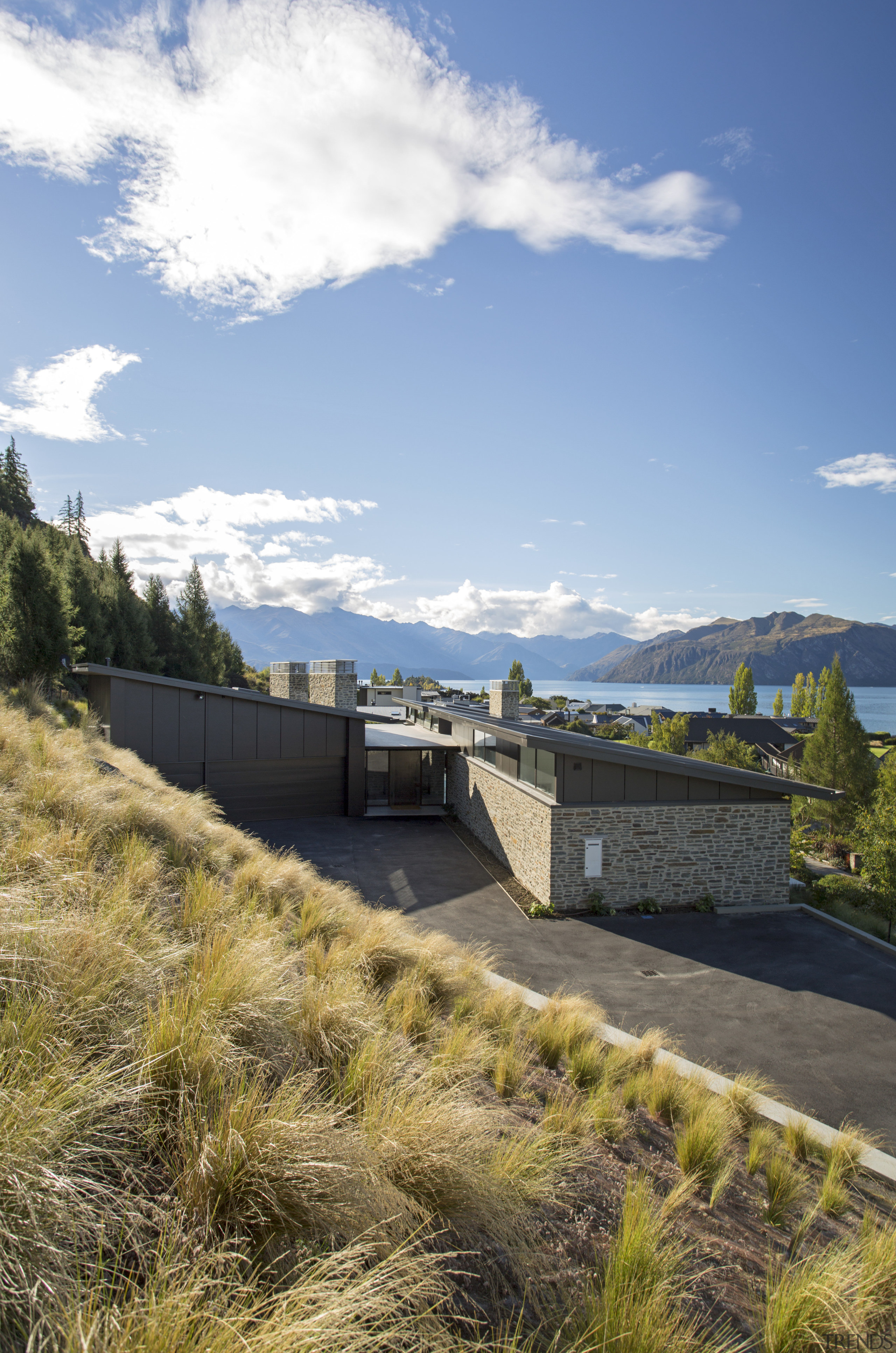 Entry to this two-pavilion home is via a architecture, cloud, coast, grass, house, landscape, mountain, plant, real estate, reservoir, sky, tree, teal