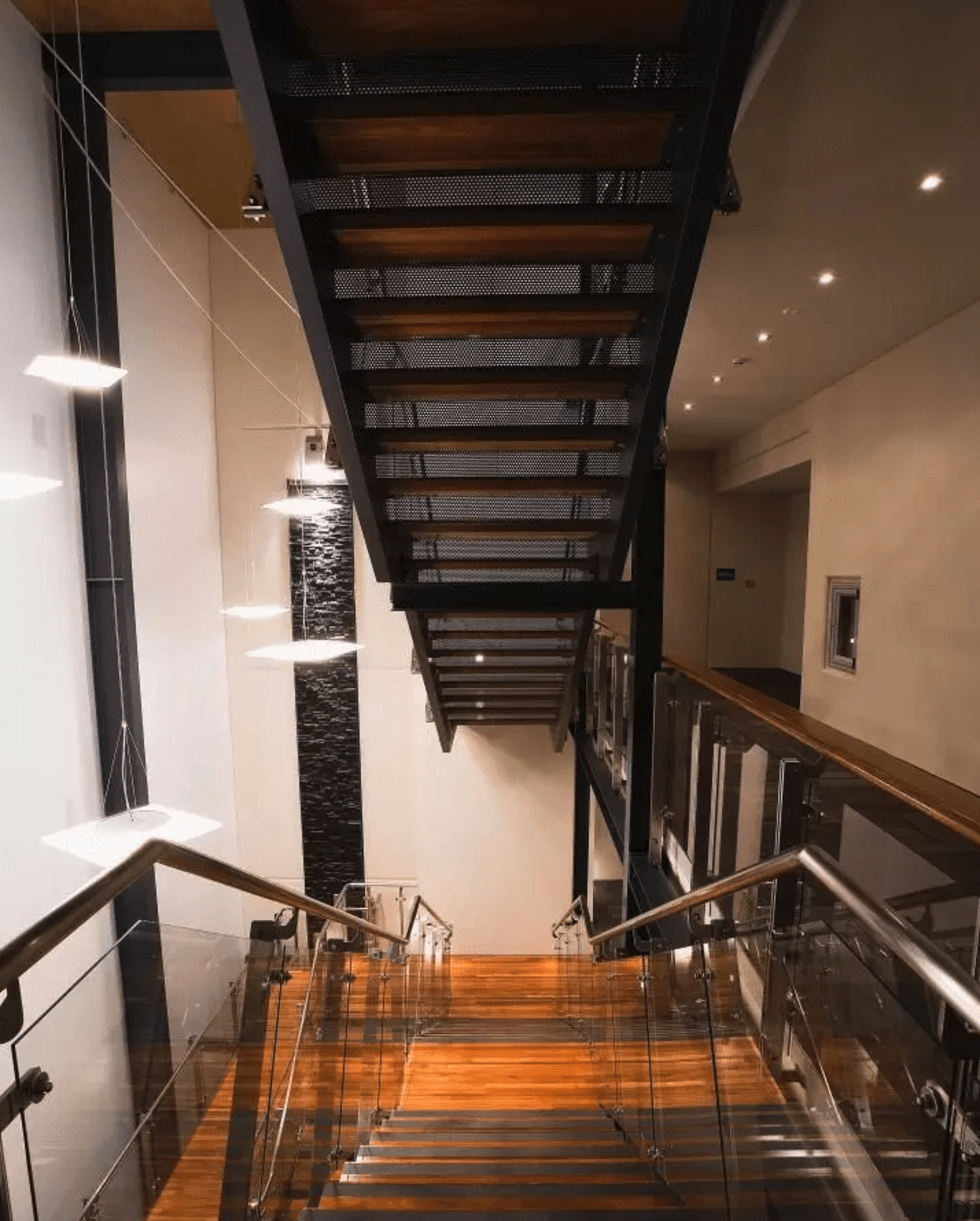 A steel-and-timber staircase is cantilevered through the atrium. apartment, architecture, ceiling, daylighting, handrail, interior design, loft, property, stairs, black, brown