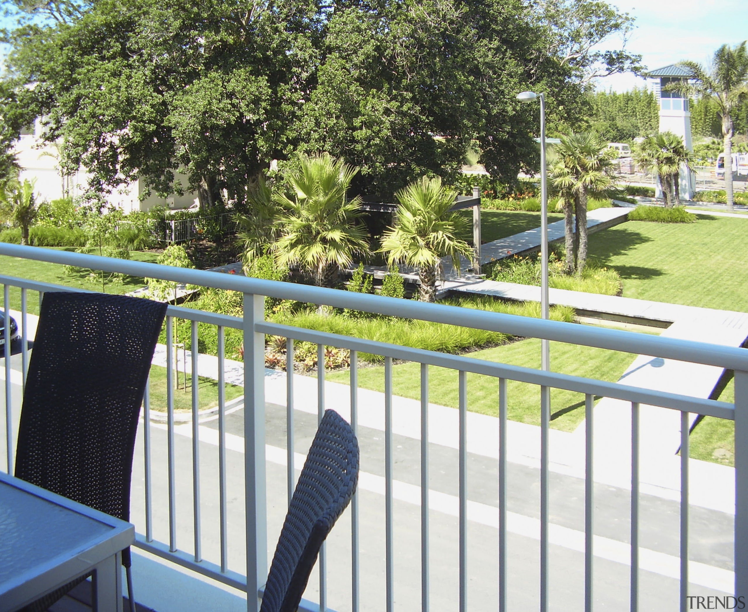 view of deck looking out into public walkways. area, fence, grass, house, outdoor structure, plant, property, real estate, recreation, tree, white