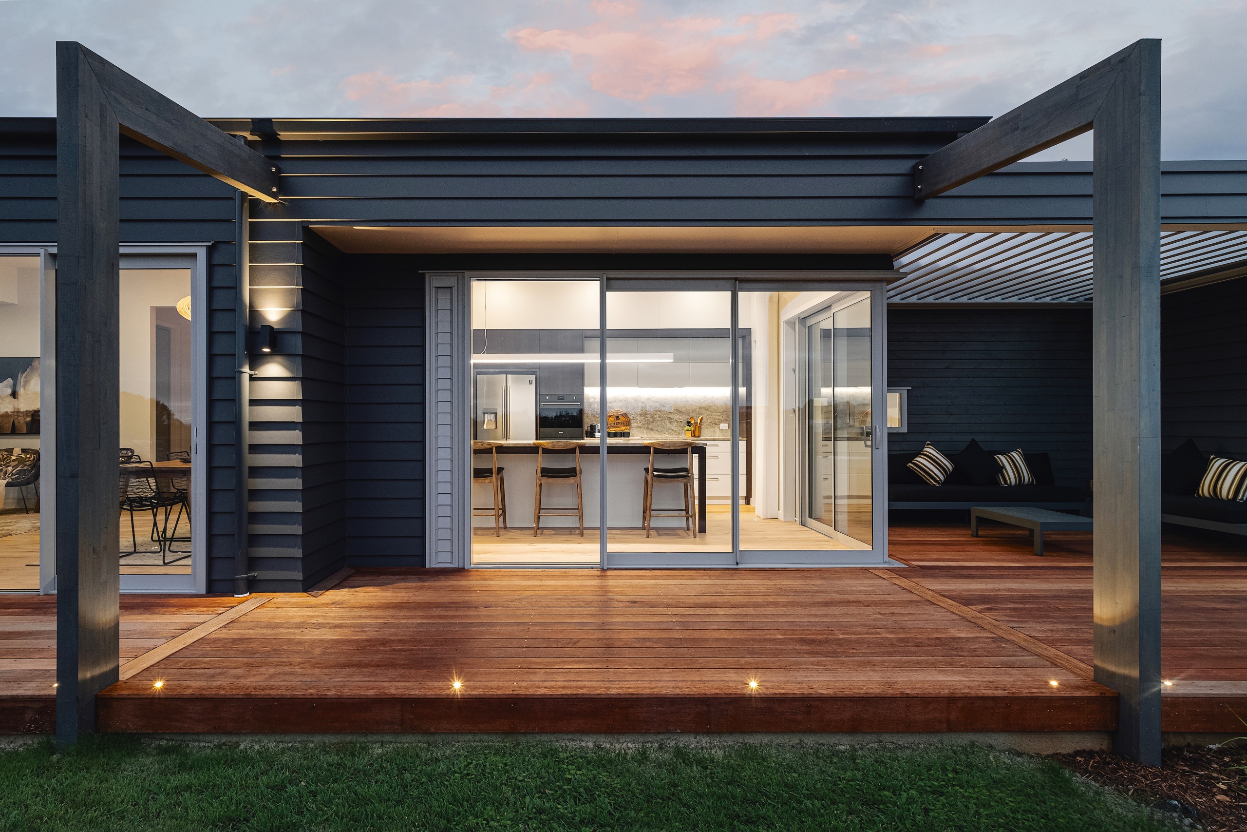 The deck, pergola and kitchen at dusk. - 