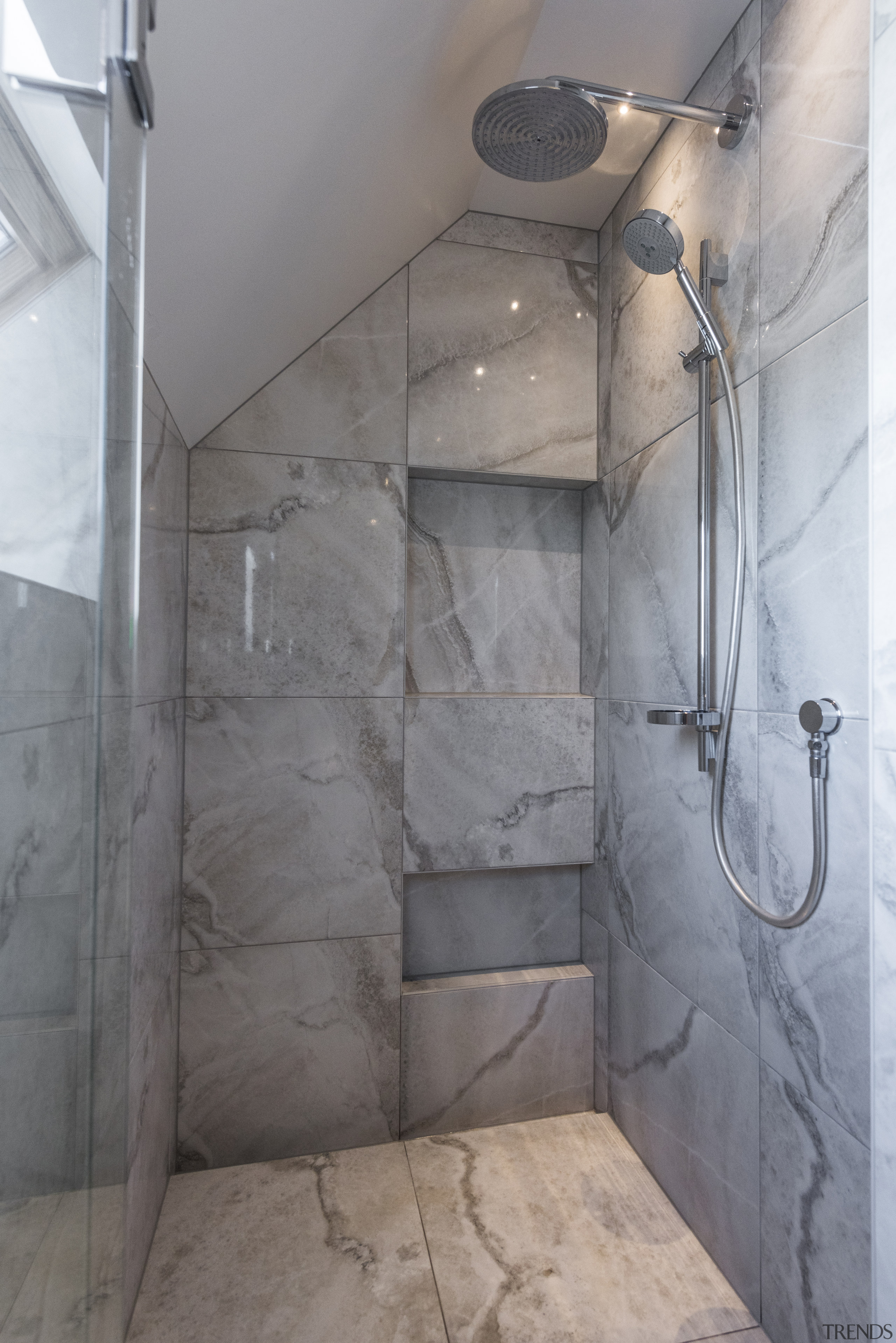 The generous shower zone is set at the architecture, bathroom, cement, floor, interior design, plumbing fixture, property, room, shower, tile, wall, gray