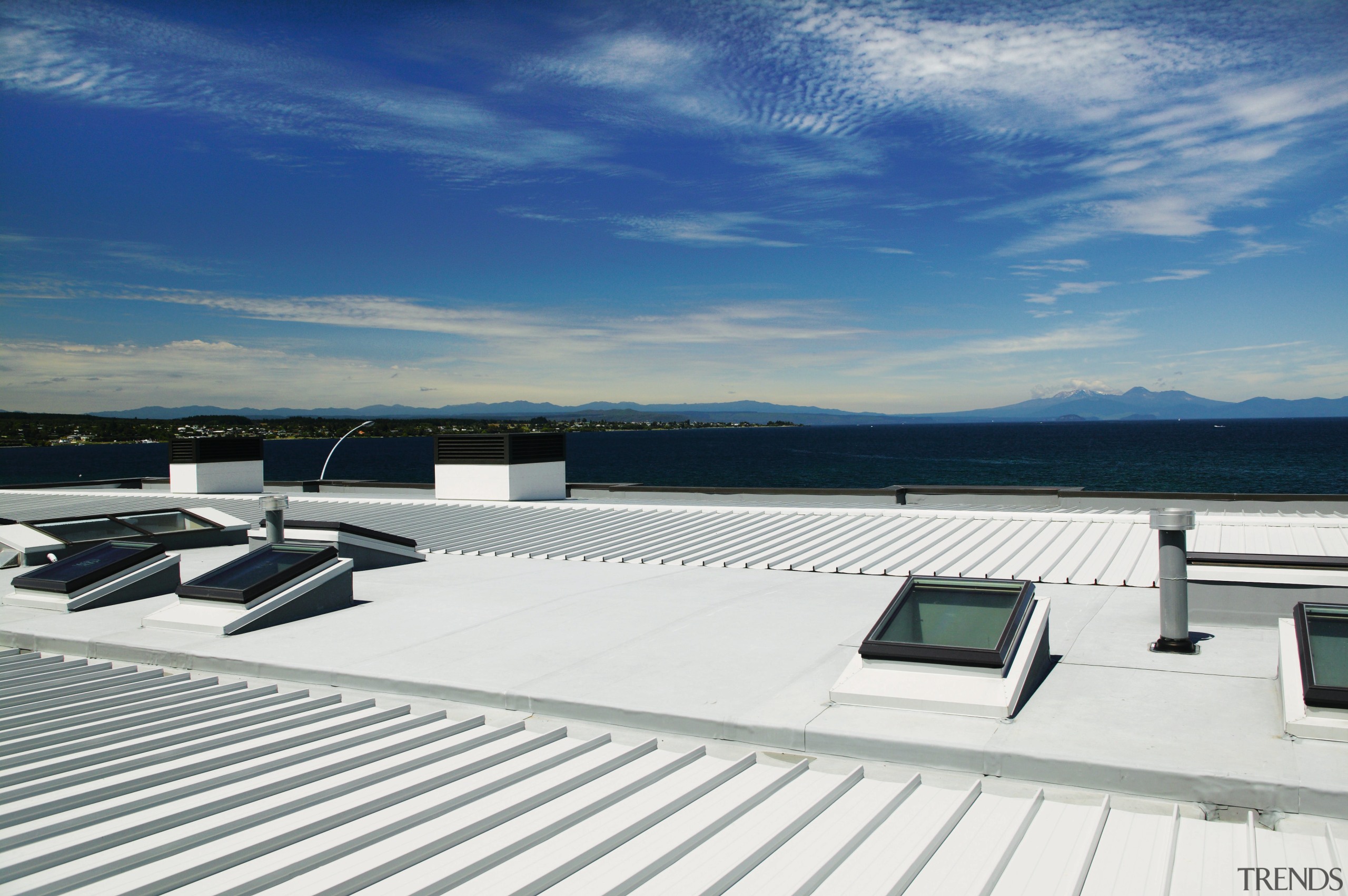 A view of a low pitched grey steel daylighting, deck, roof, sky, water, yacht, white