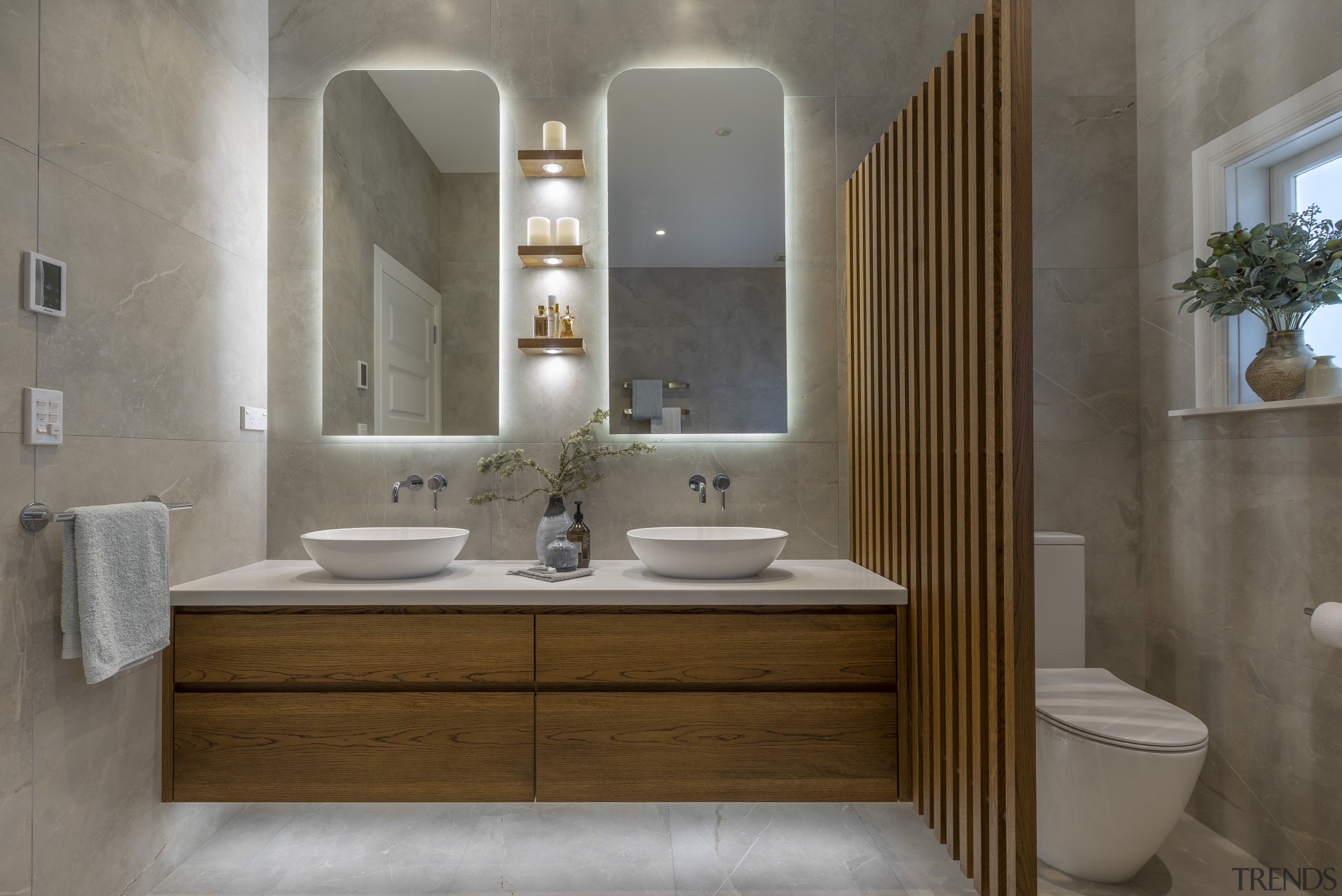 A wood baton privacy wall separates toilet from architecture, bathroom, bathroom accessory, bathroom cabinet, beige, building, ceramic, floor, furniture, interior design, material property, plumbing fixture, property, restroom, room, sink, tap, tile, toilet, gray, brown