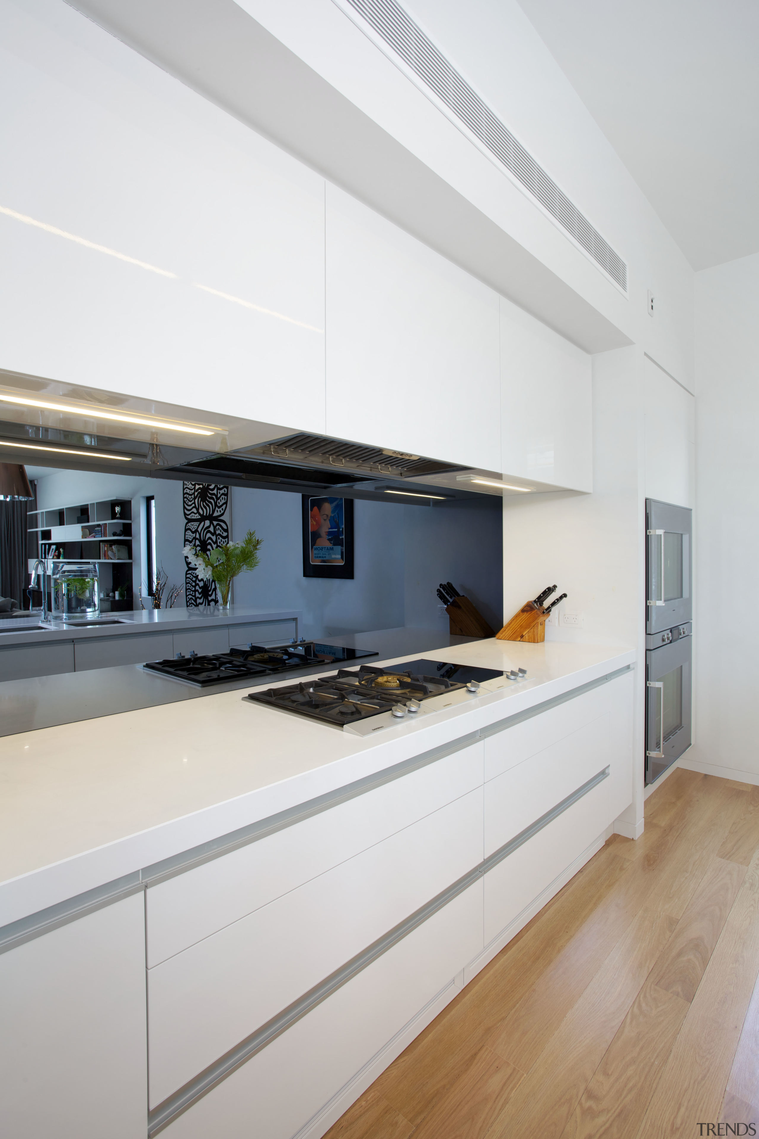 A mirrored splashback adds visual depth to this architecture, countertop, house, interior design, kitchen, real estate, white, gray