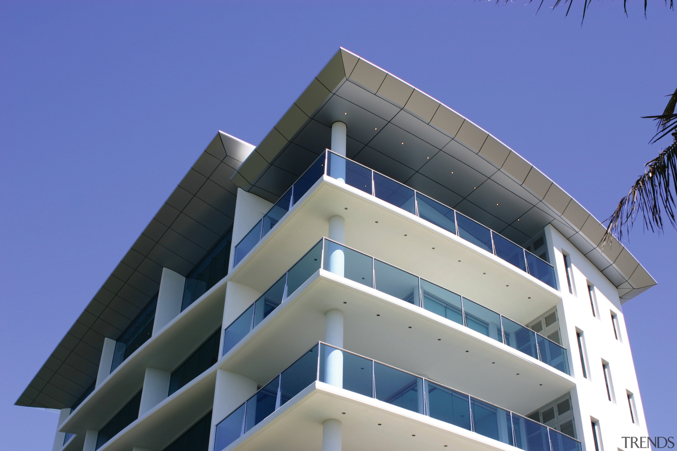 Exterior of multi-level apartment building with white cladding, apartment, architecture, building, commercial building, condominium, corporate headquarters, daylighting, daytime, elevation, facade, headquarters, mixed use, real estate, residential area, sky, tower block, blue