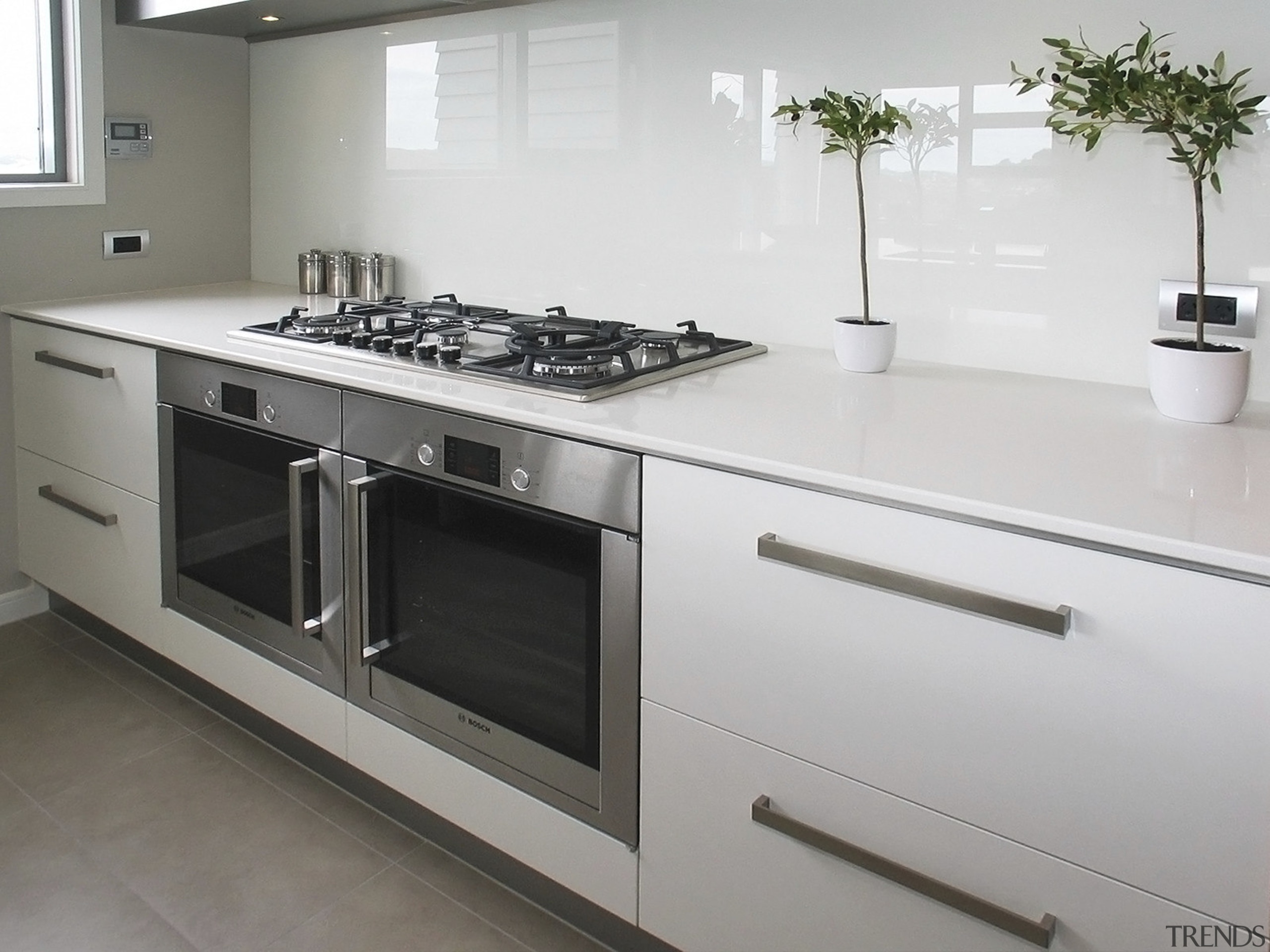 View of a kitchen which was designed by countertop, cuisine classique, gas stove, home appliance, kitchen, kitchen appliance, kitchen stove, major appliance, gray, white