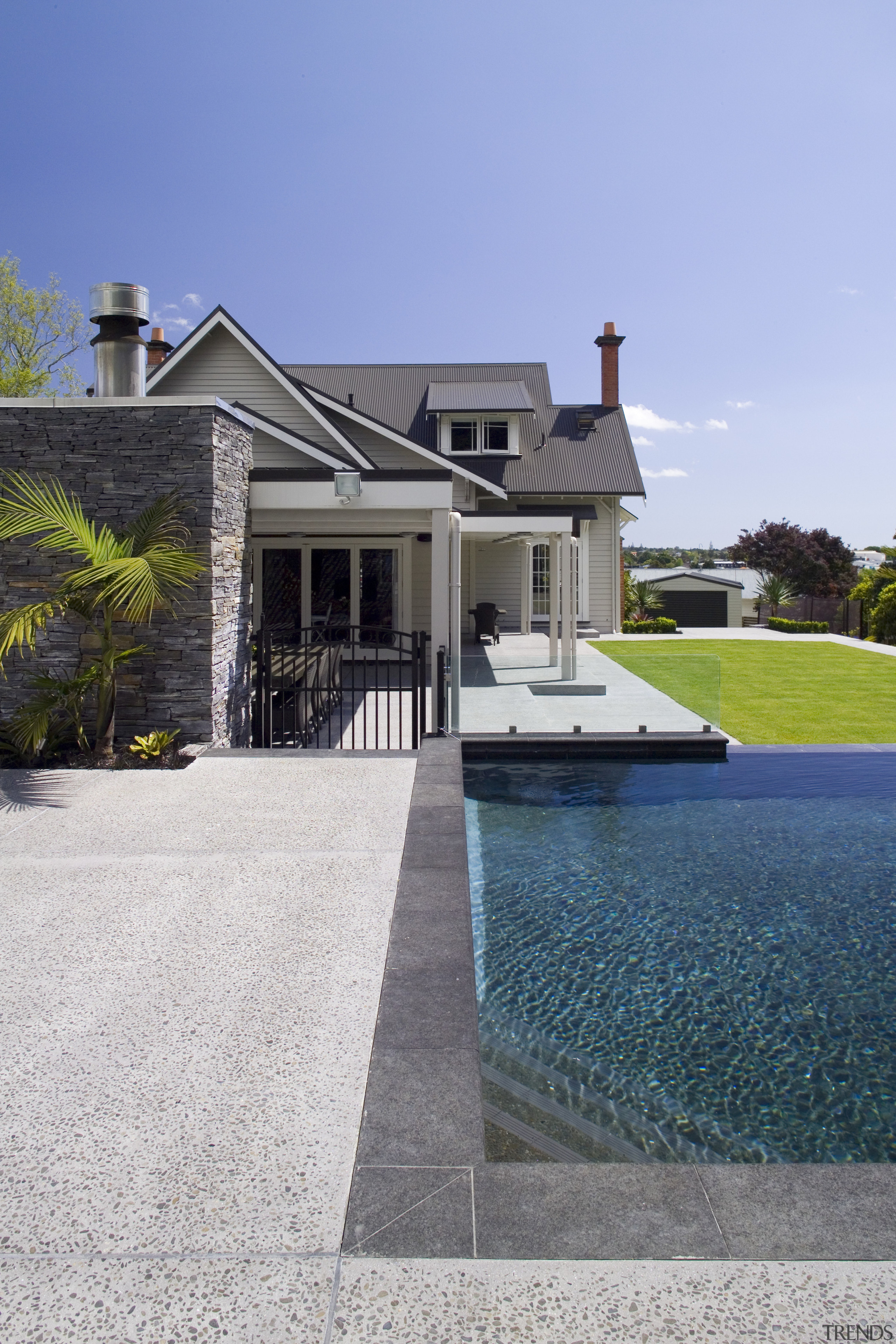 Stonework frames the pool and is also introduced architecture, backyard, cottage, driveway, estate, facade, home, house, landscaping, mansion, outdoor structure, property, real estate, residential area, roof, siding, sky, suburb, swimming pool, villa, walkway, water, window, teal