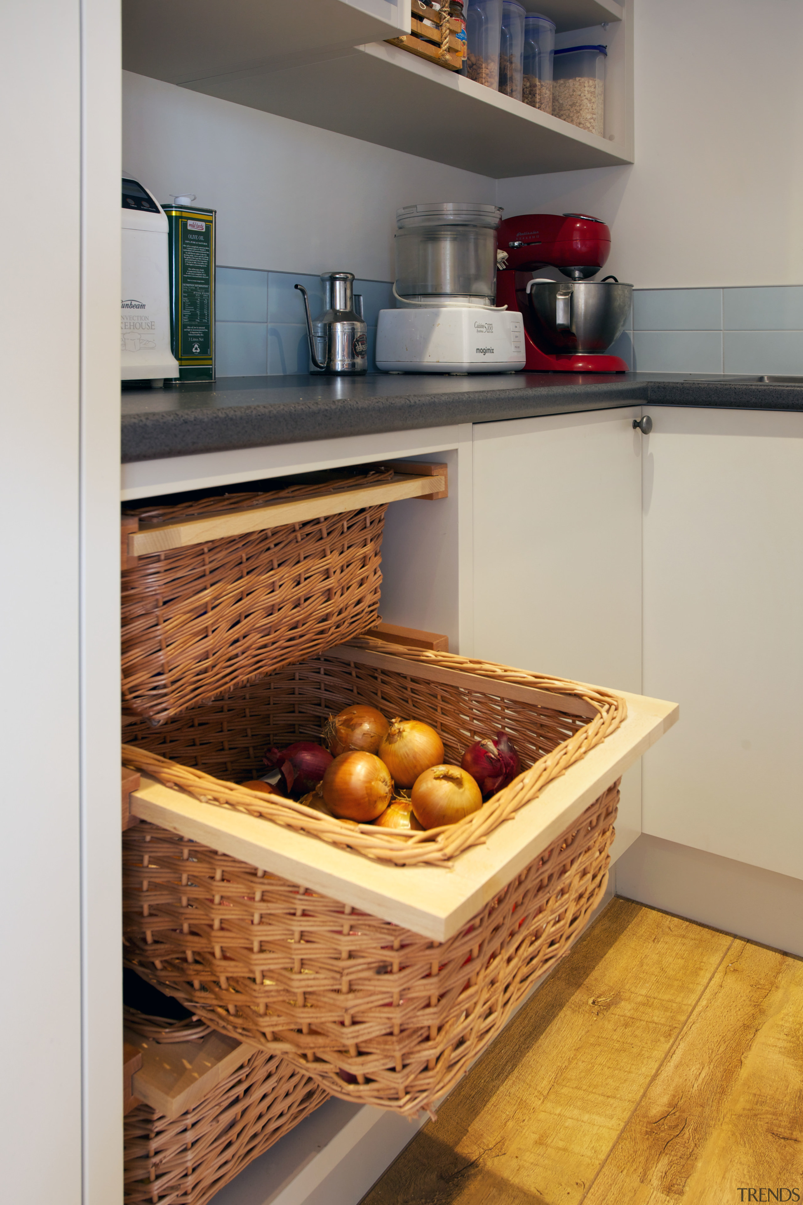 There are pull-out wicker baskets for storing vegetables countertop, flooring, kitchen, gray