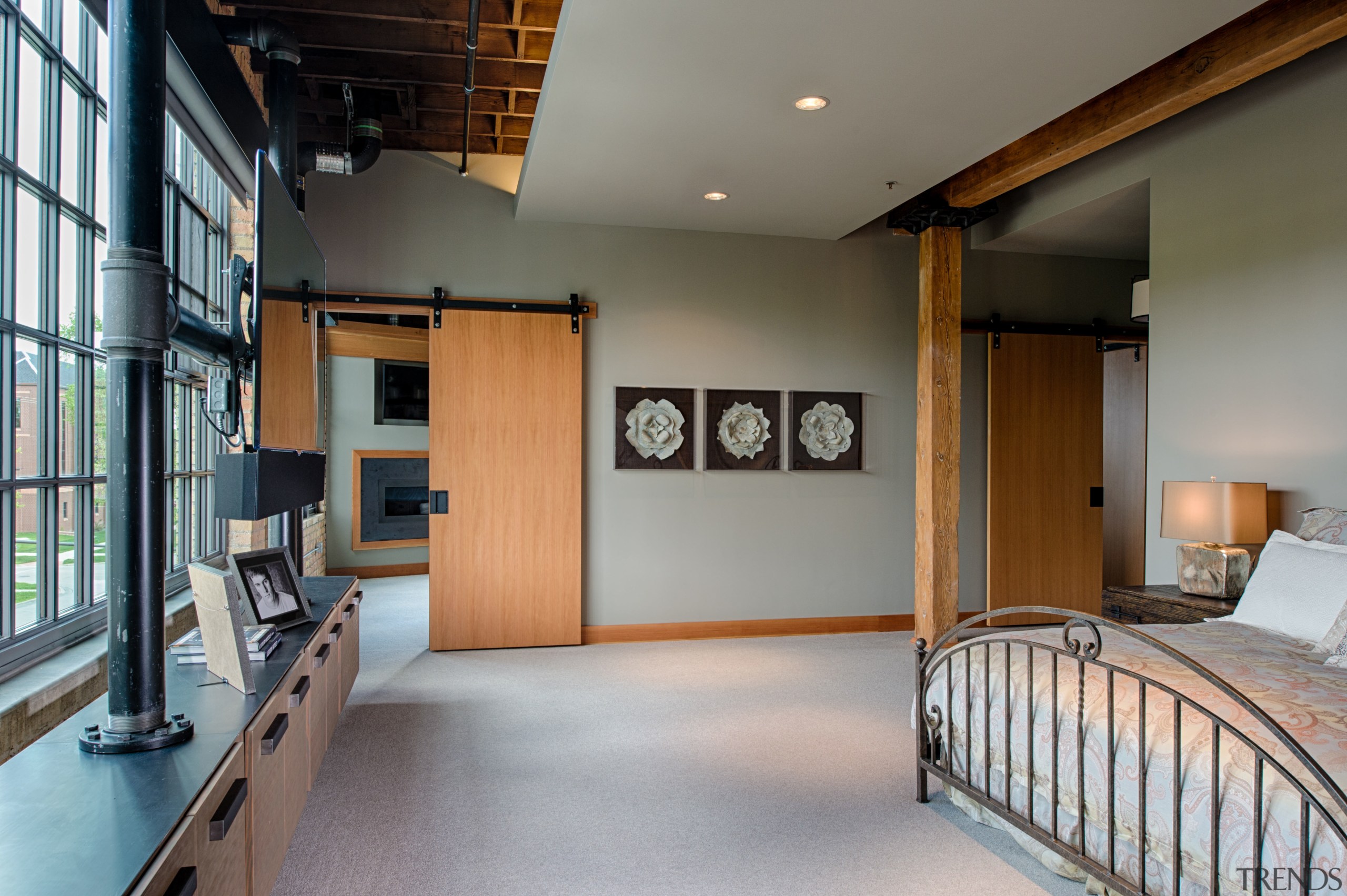 This bedroom in a converted loft-style building features architecture, ceiling, floor, flooring, interior design, real estate, room, gray