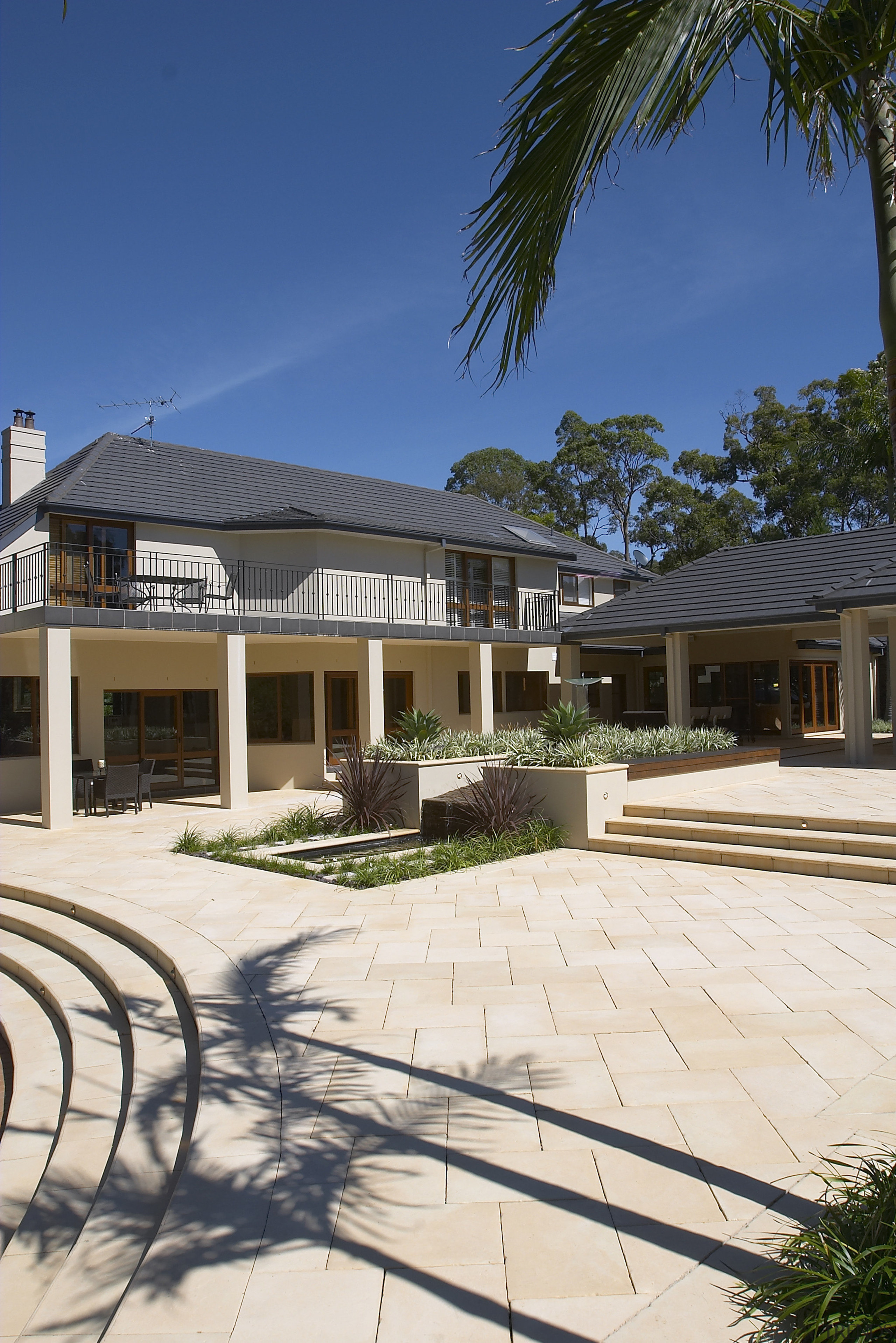 Exterior view of a home which was designed arecales, backyard, cottage, elevation, estate, facade, home, house, landscaping, mansion, neighbourhood, outdoor structure, palm tree, property, real estate, residential area, resort, roof, siding, sky, villa, walkway, window, white, blue