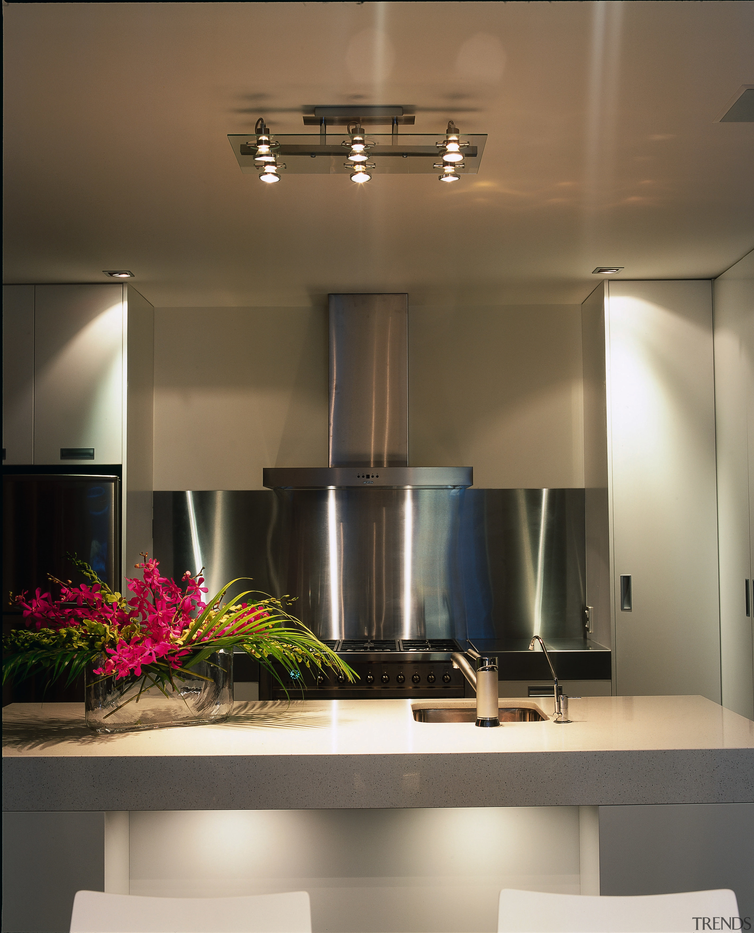 Kitchen with grey cabinetry, large stainless steel splashback, ceiling, countertop, interior design, kitchen, light fixture, lighting, under cabinet lighting, brown, gray