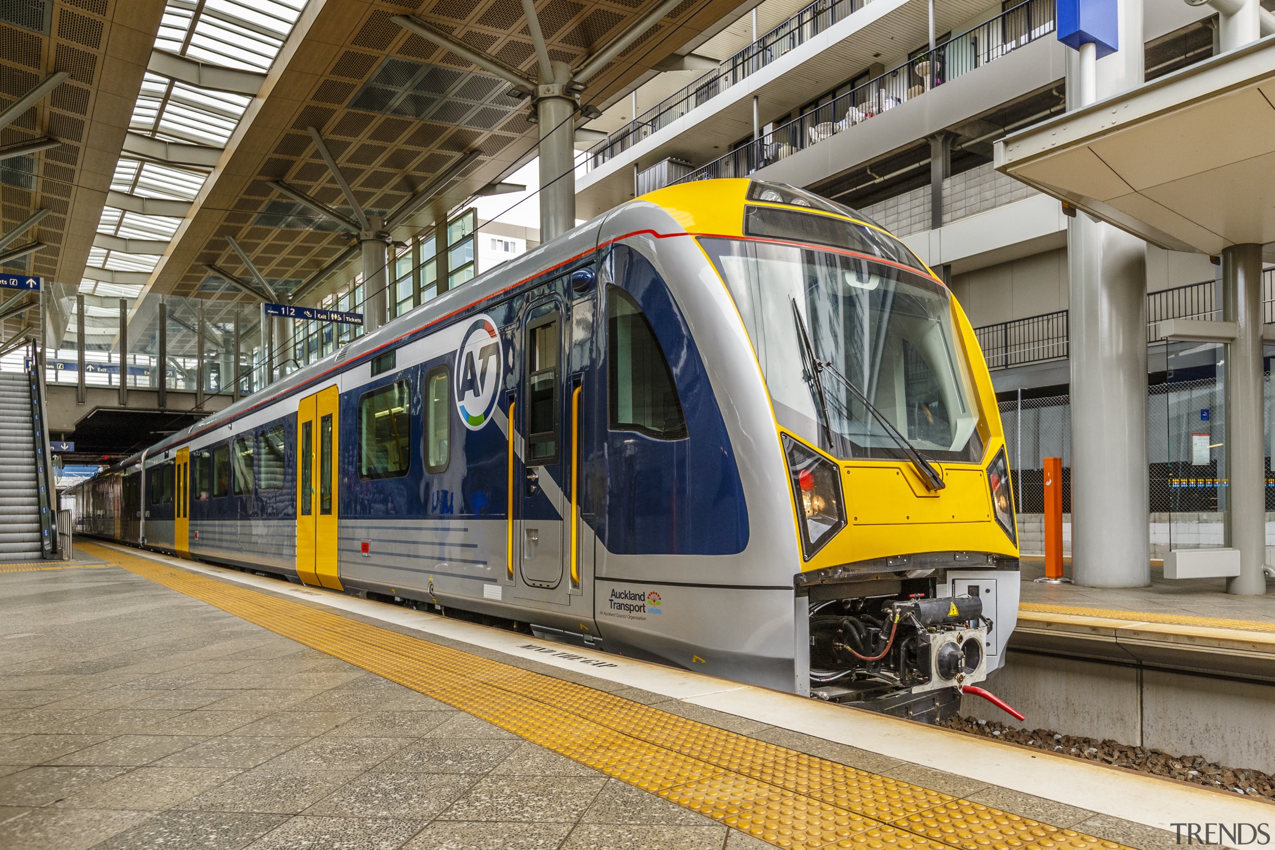 With ultra-modern design and sleek blue and yellow locomotive, metropolis, metropolitan area, mode of transport, public transport, rail transport, railroad car, rapid transit, rolling stock, track, train, train station, transport, urban area, gray, brown