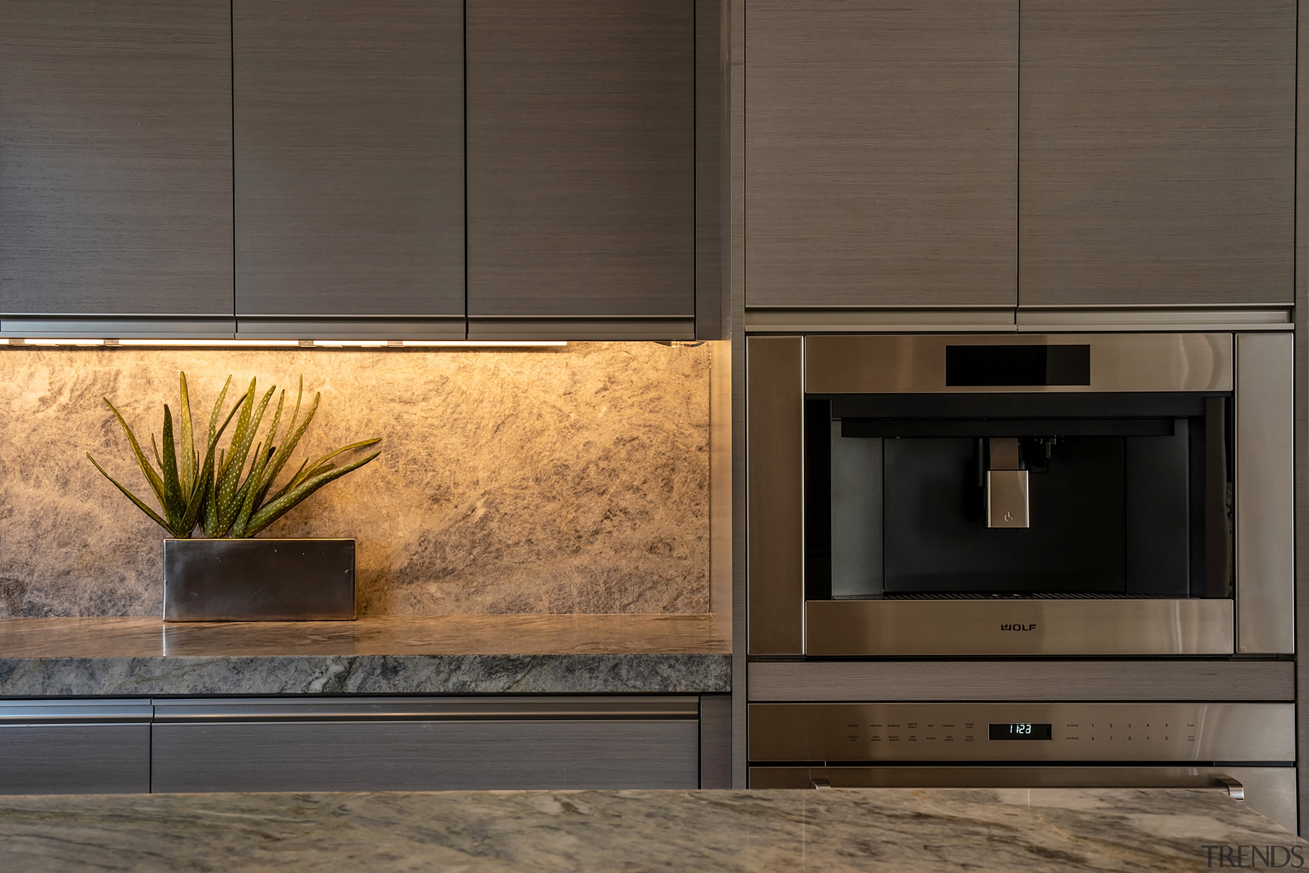 Under-cabinet lighting highlights the leathered stone surfaces. 