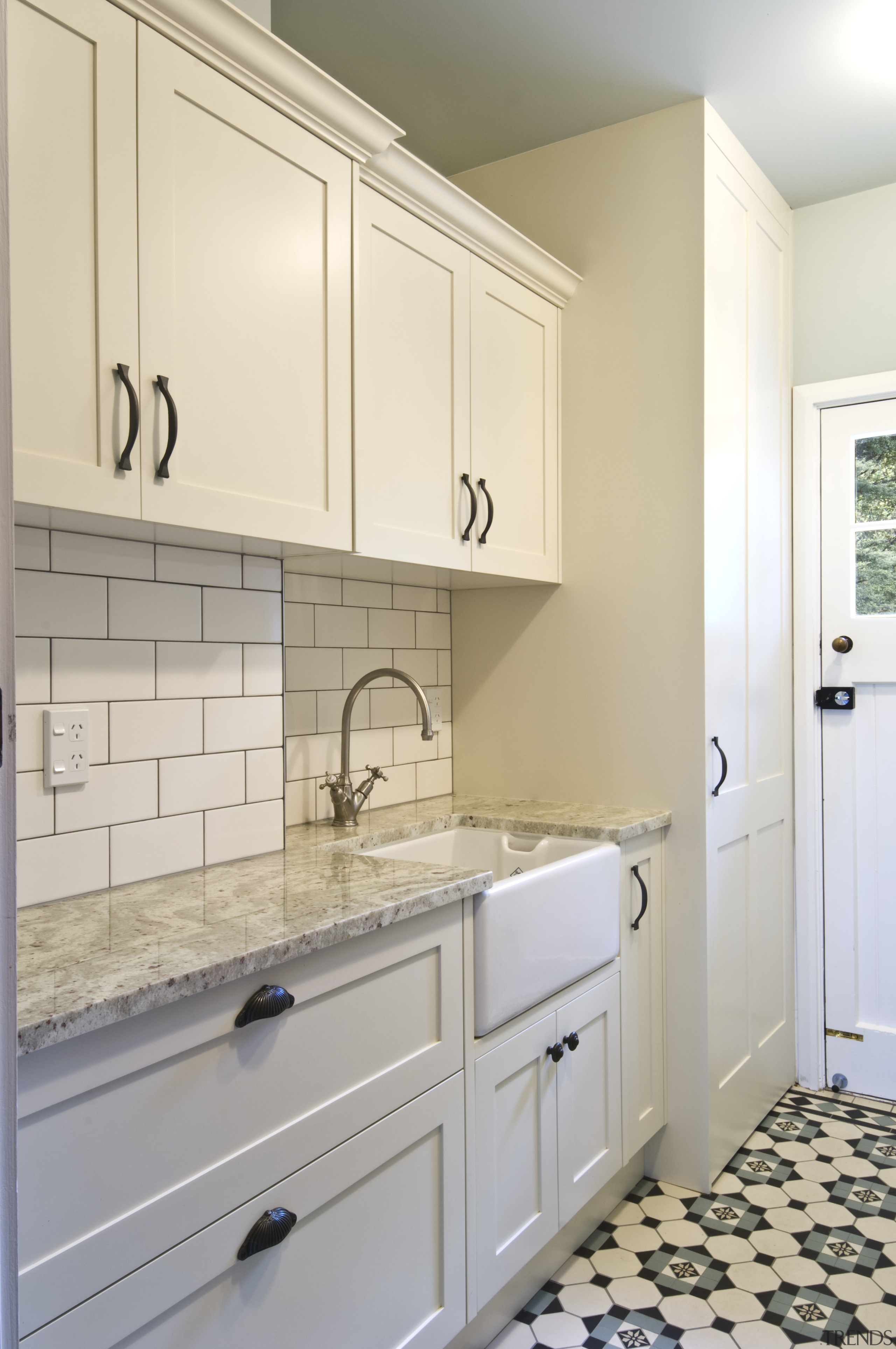 View of laundry, featuring a white butler's sink, bathroom, bathroom accessory, bathroom cabinet, cabinetry, countertop, cuisine classique, floor, flooring, home, home appliance, interior design, kitchen, laundry room, room, sink, tile, wall, gray