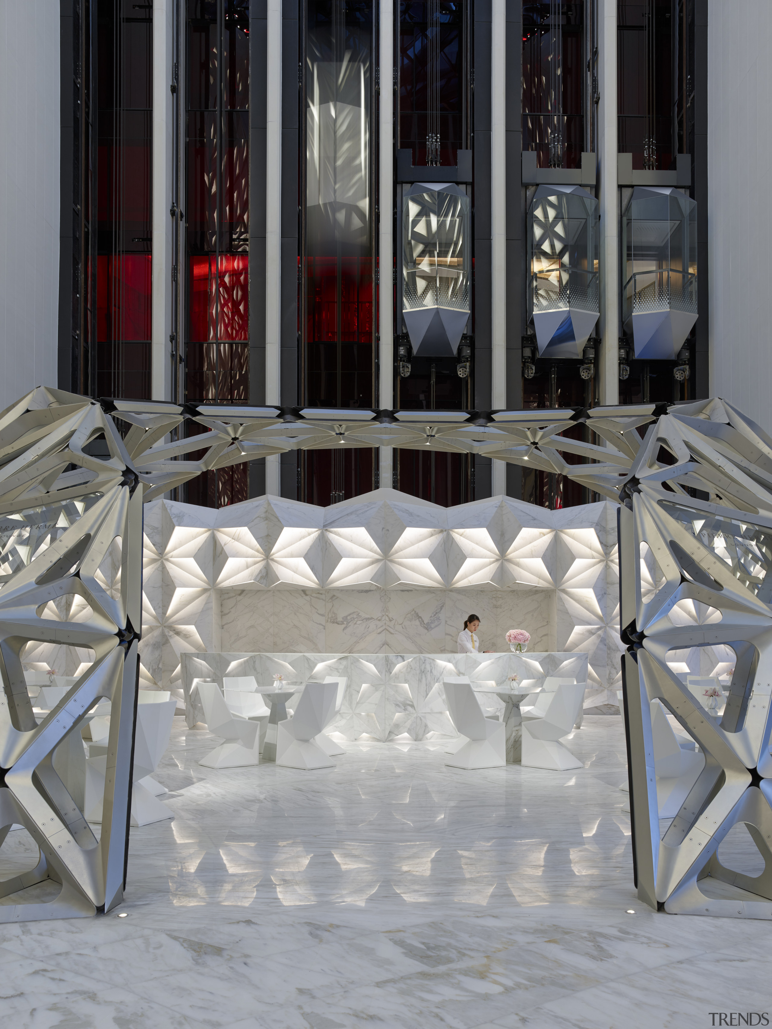 Glass elevators rise behind the faceted reception desk chair, floor, flooring, furniture, table, window, gray, black