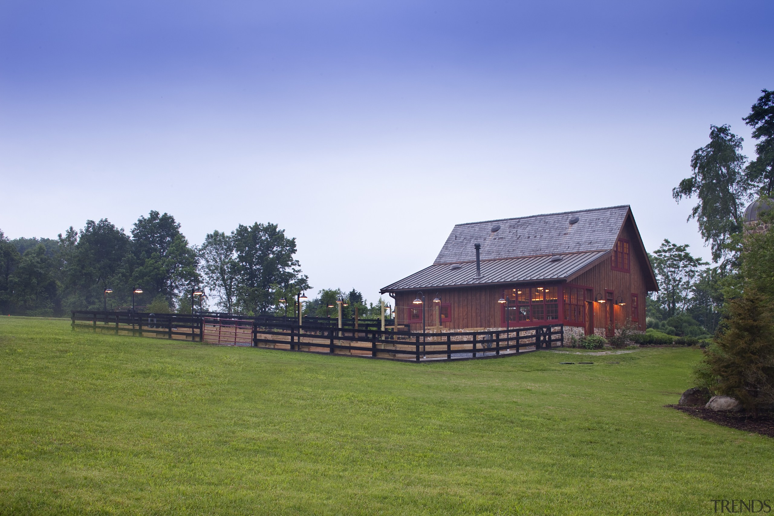 View of wooden building with lawn in foreground. barn, cottage, estate, farm, farmhouse, field, grass, grassland, home, house, land lot, landscape, log cabin, meadow, pasture, property, real estate, rural area, sky, tree, blue