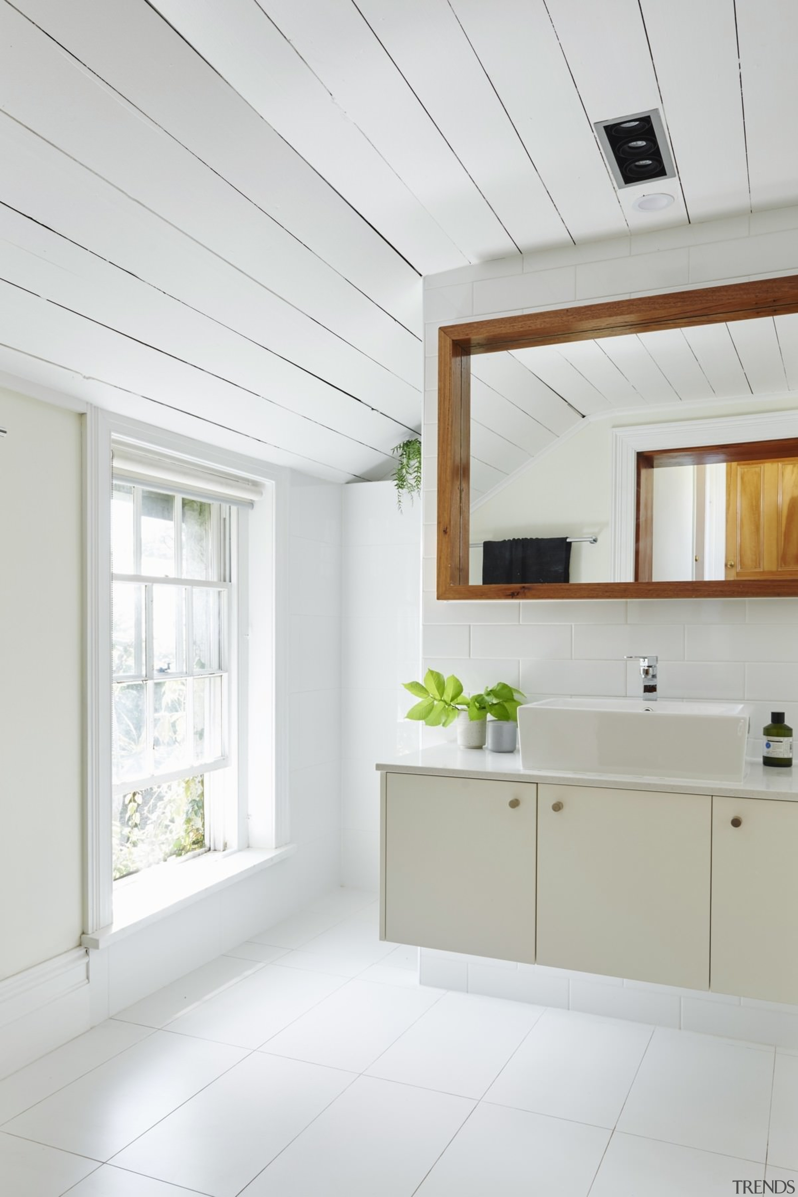 The bathroom feels spacious and open, largely thanks architecture, ceiling, daylighting, floor, flooring, home, house, interior design, real estate, window, white, gray