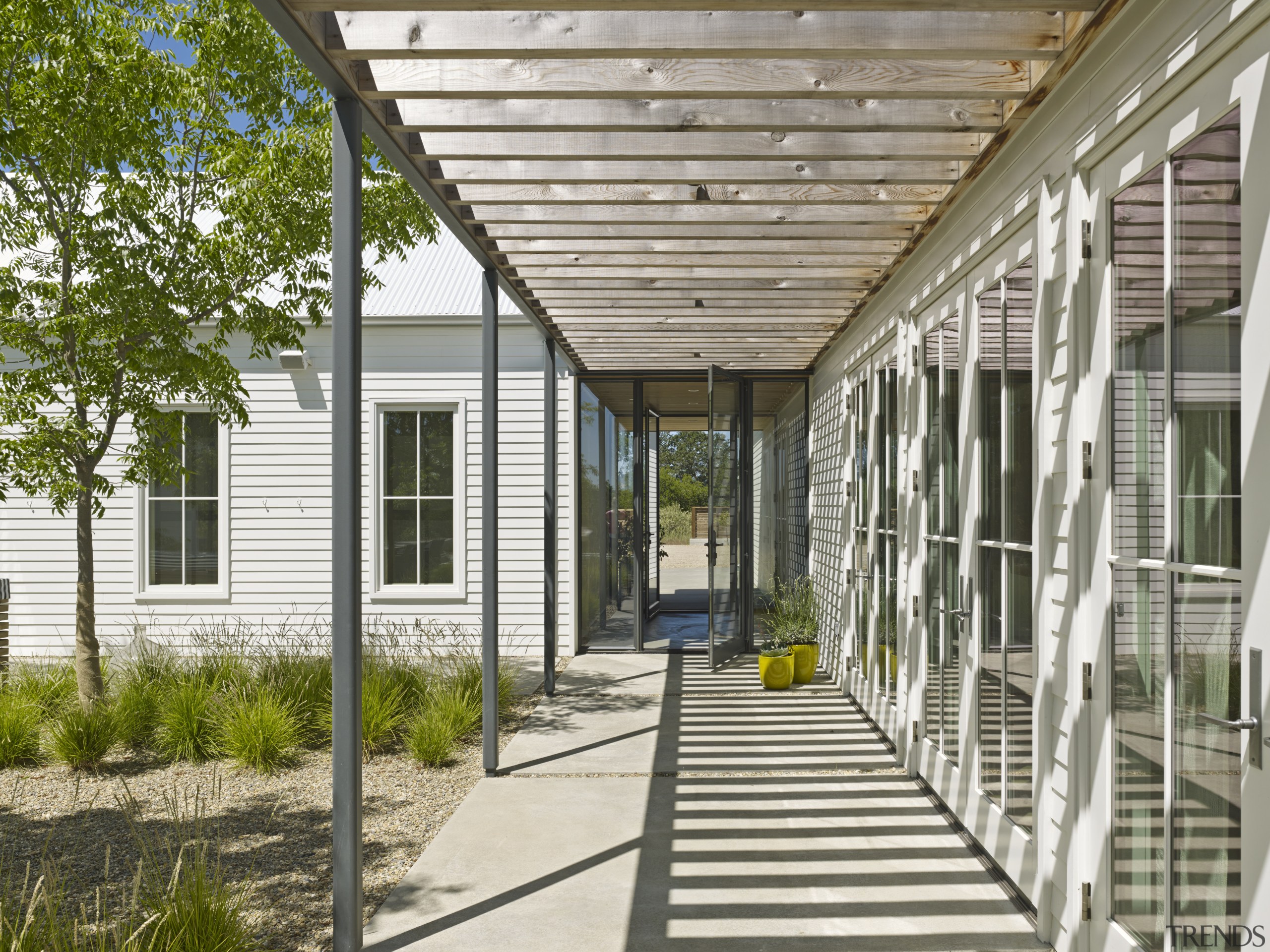 A steel and wood trellis on this pergola architecture, courtyard, home, house, porch, real estate, walkway, white, brown, gray