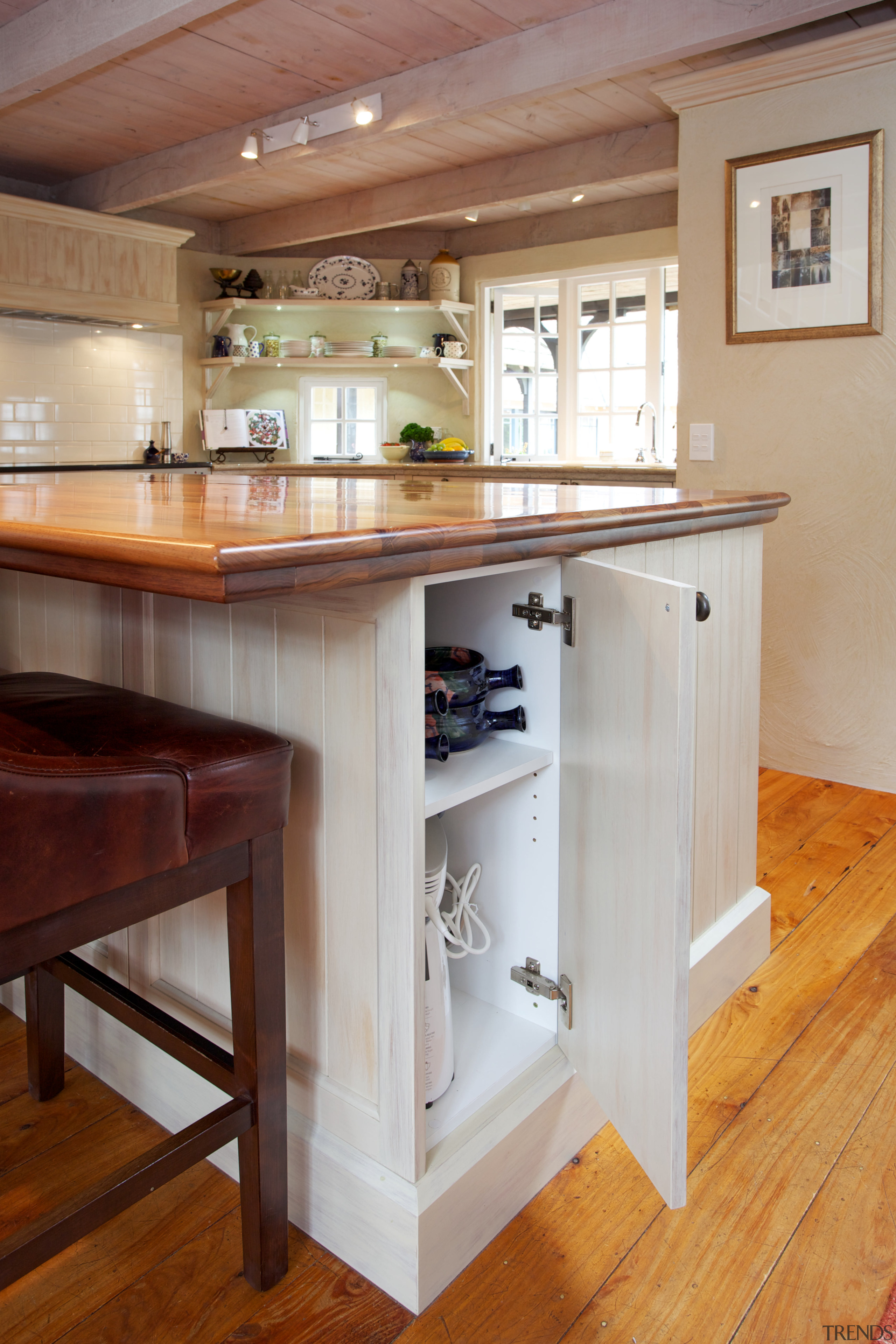 The island counter in this kitchen features ample cabinetry, countertop, cuisine classique, drawer, floor, flooring, furniture, hardwood, interior design, kitchen, room, table, wood, wood flooring, wood stain, gray, brown