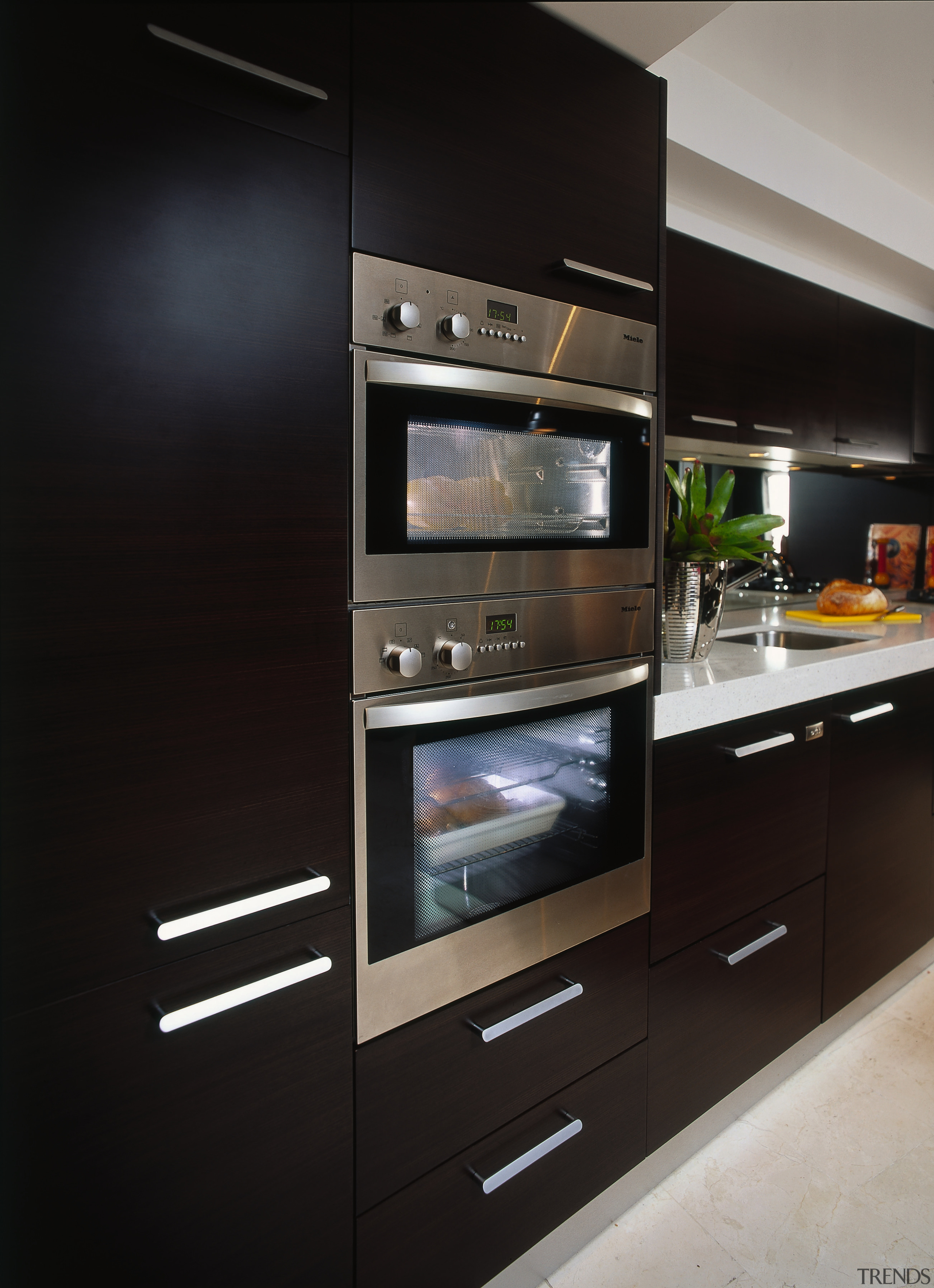 Kitchen with dark timber veneer cabinetry with stainless countertop, home appliance, kitchen, kitchen appliance, kitchen stove, major appliance, oven, black