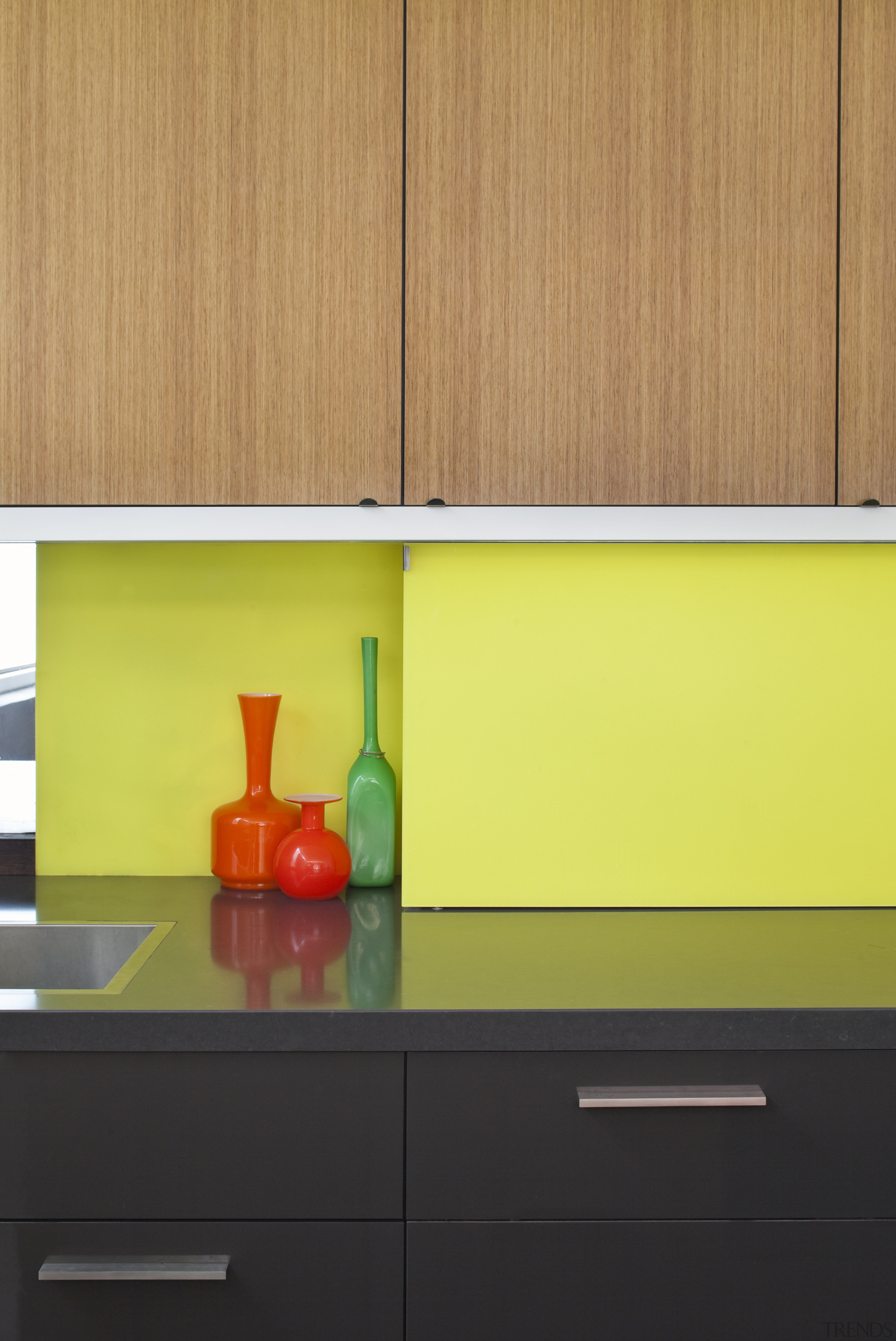 A bright yellow splashback is a feature of countertop, interior design, kitchen, orange, product design, shelf, shelving, table, wall, yellow, orange, yellow