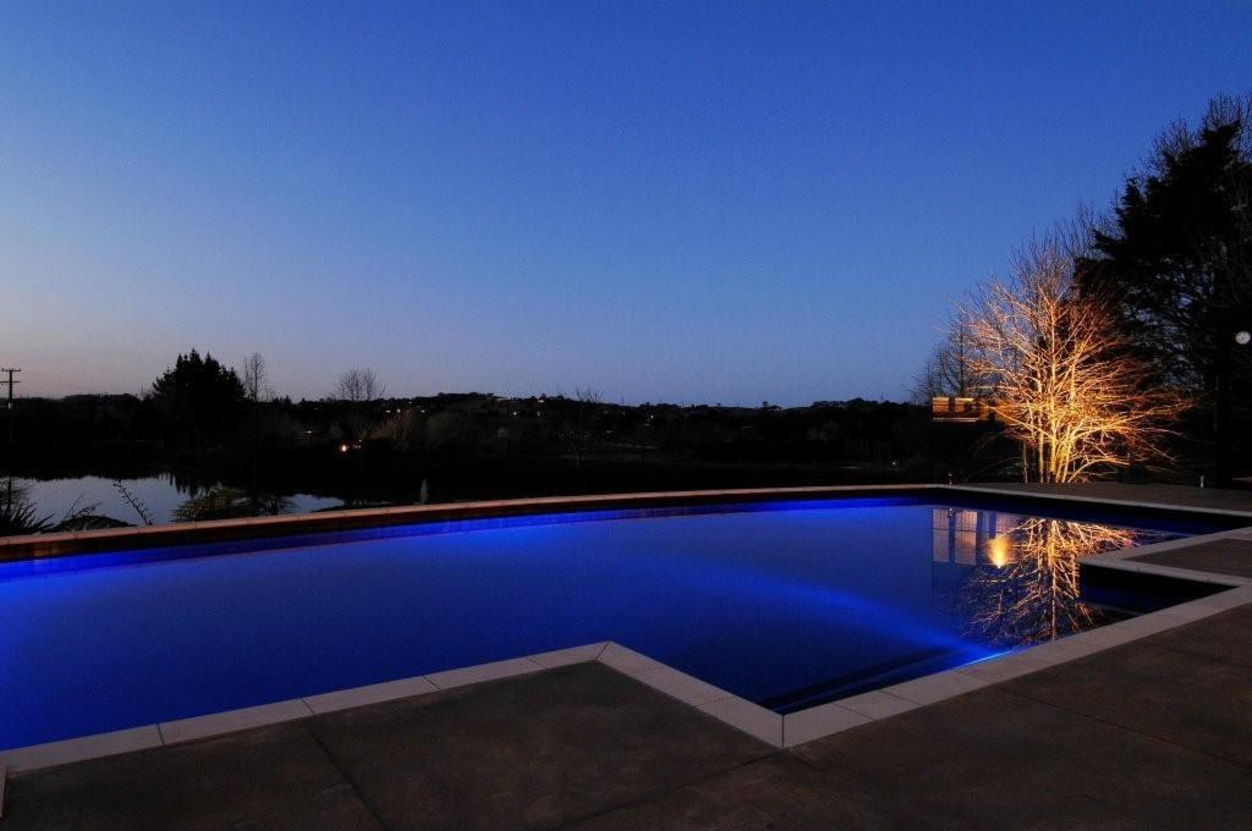 Well balanced lighting give this concrete pool a blue, estate, evening, home, house, landscape lighting, leisure, light, lighting, plant, property, real estate, reflection, residential area, sky, swimming pool, water, blue, black