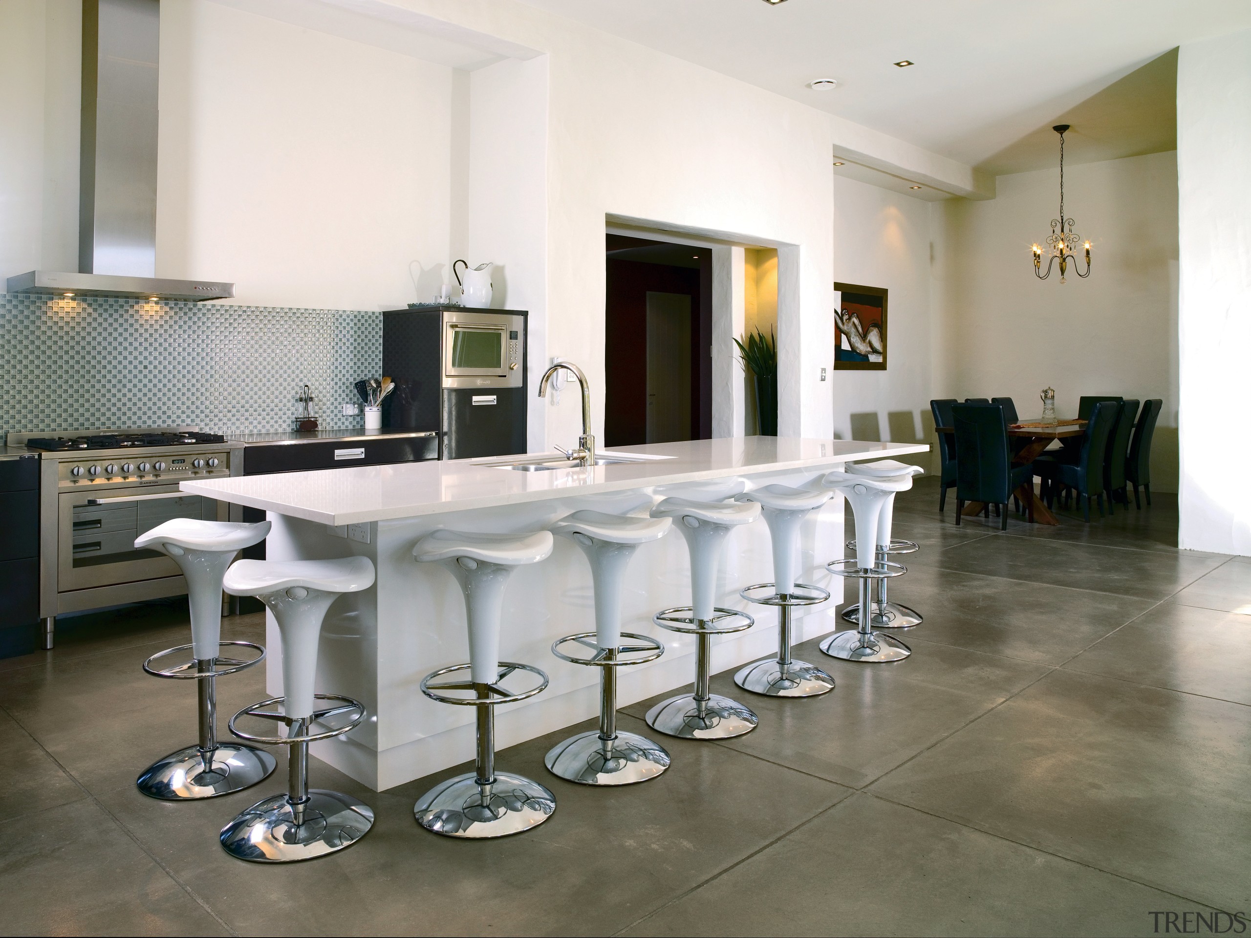 Open plan kitchen with black cabinetry and white chair, countertop, dining room, floor, flooring, furniture, interior design, property, real estate, room, table, tile, white, gray