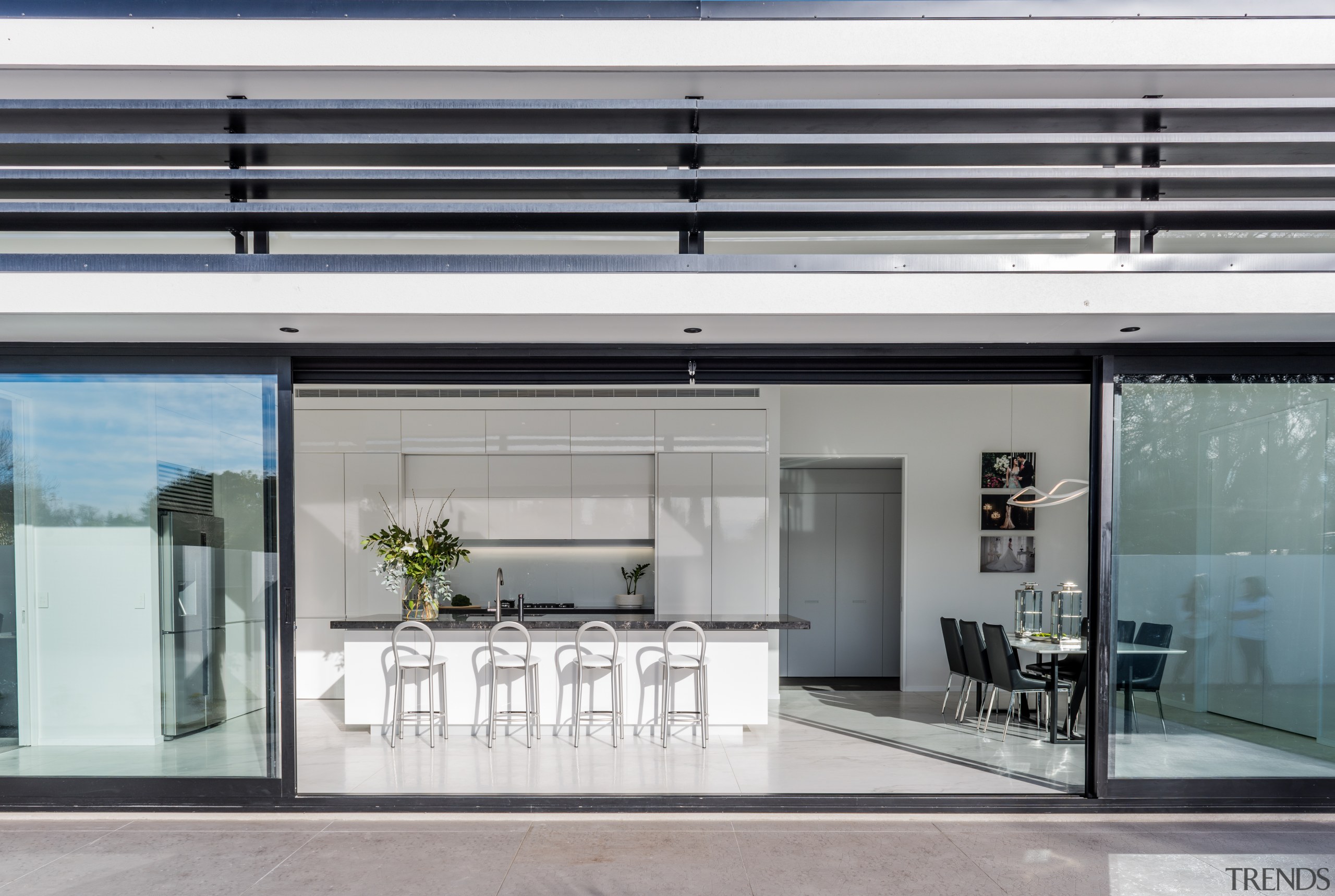 With handleless cabinetry closed, this pristine white entertainer’s door, glass, house, interior design, window, gray