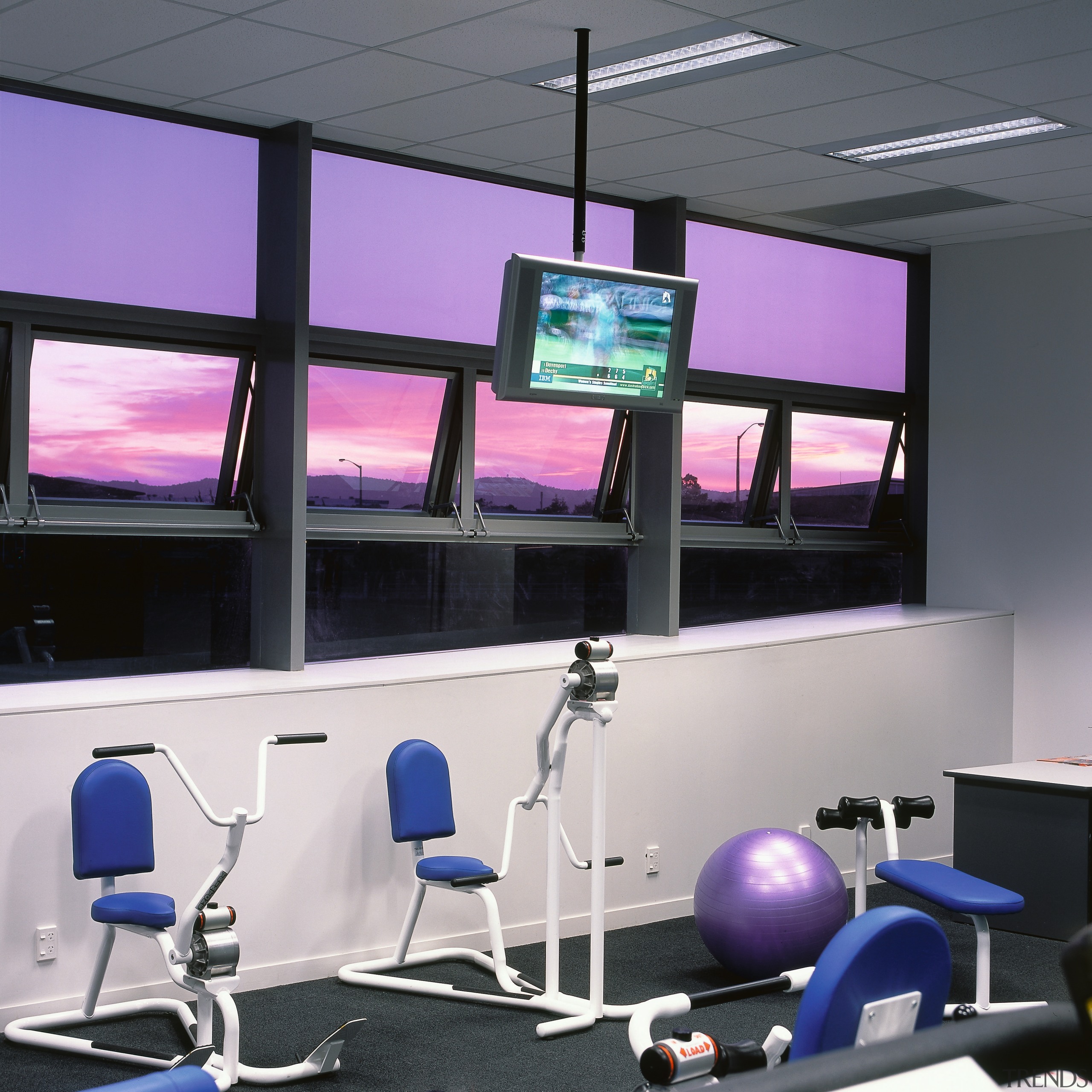 LCD television screen suspended from ceiling in gym. display device, gym, multimedia, office, product design, purple, room, sport venue, structure, technology, gray