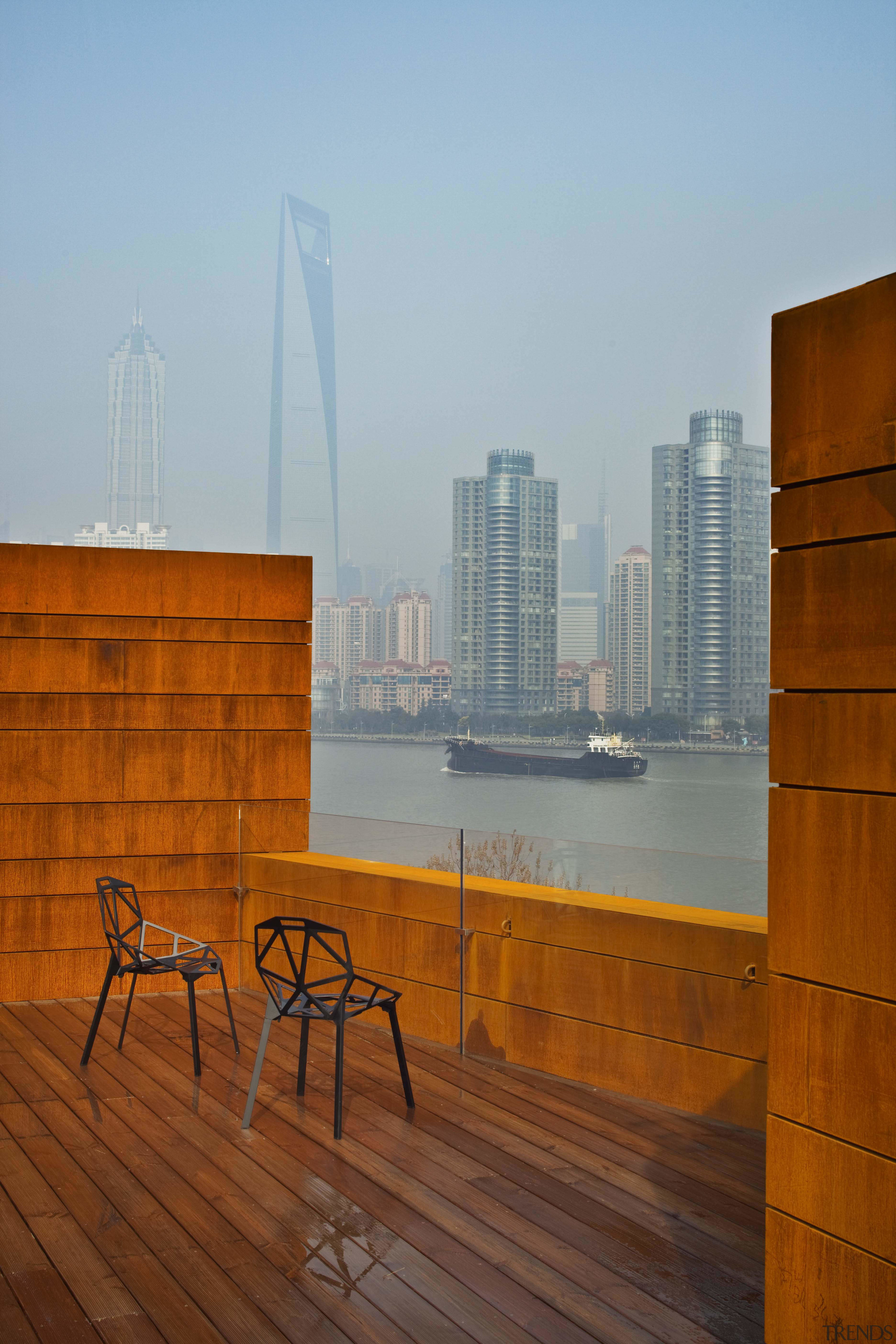View of a contemporary boutique hotel in Shanghai. apartment, architecture, building, city, horizon, morning, real estate, reflection, sky, skyline, skyscraper, sunlight, wall, water, wood, brown, gray