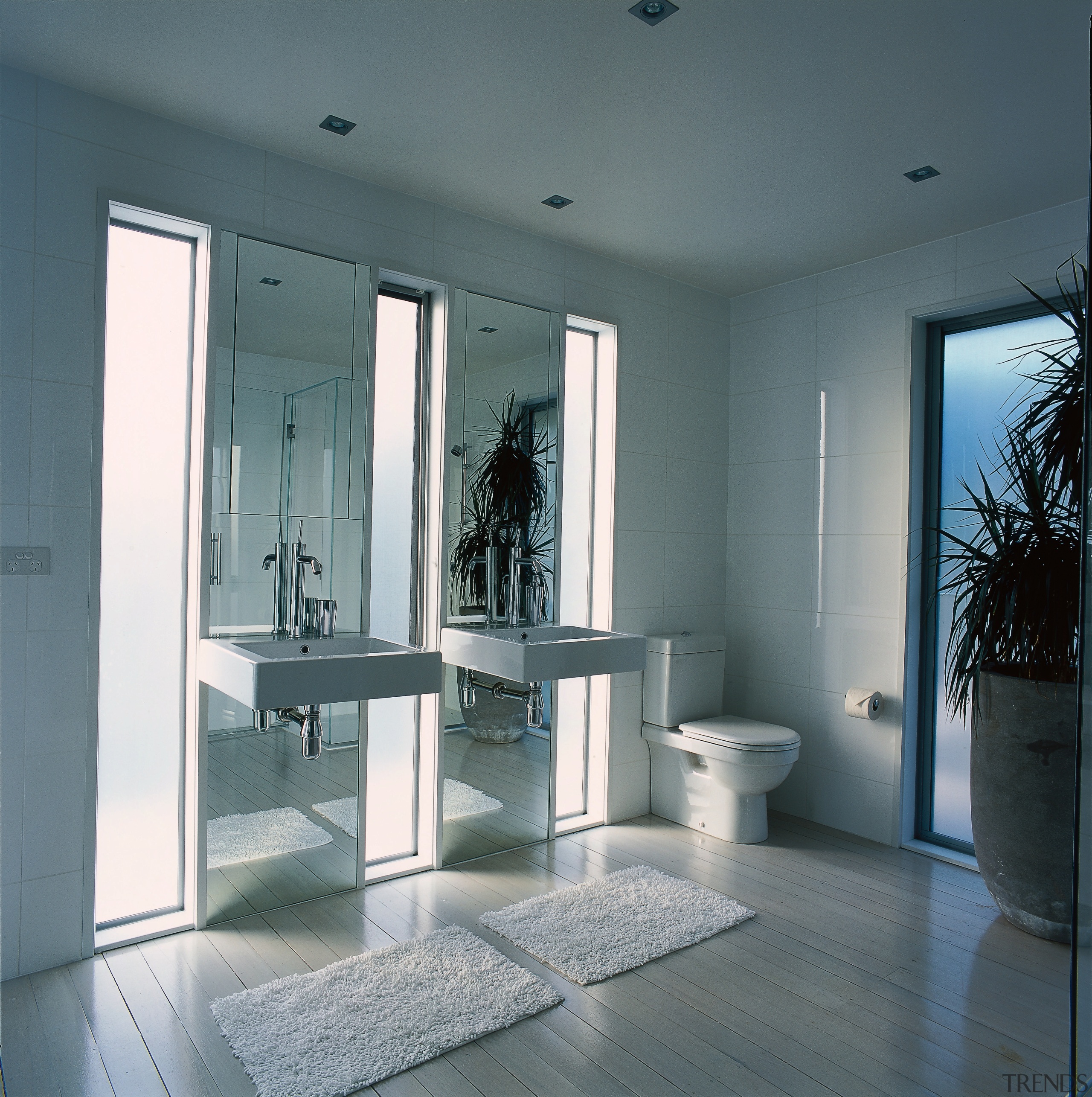 A view of a bathroom featuring basins, toilet daylighting, door, floor, glass, interior design, structure, window, gray