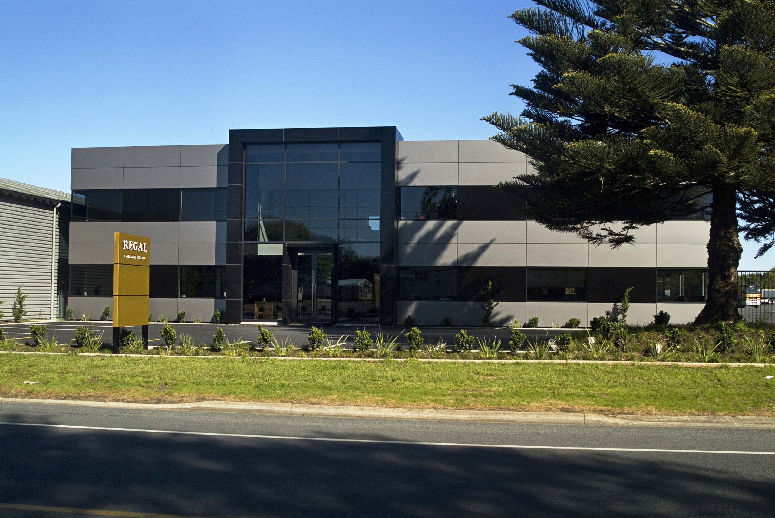 Exterior view from the roadside. Gardens have been architecture, building, car, corporate headquarters, facade, home, house, property, real estate, sky, transport, tree, black