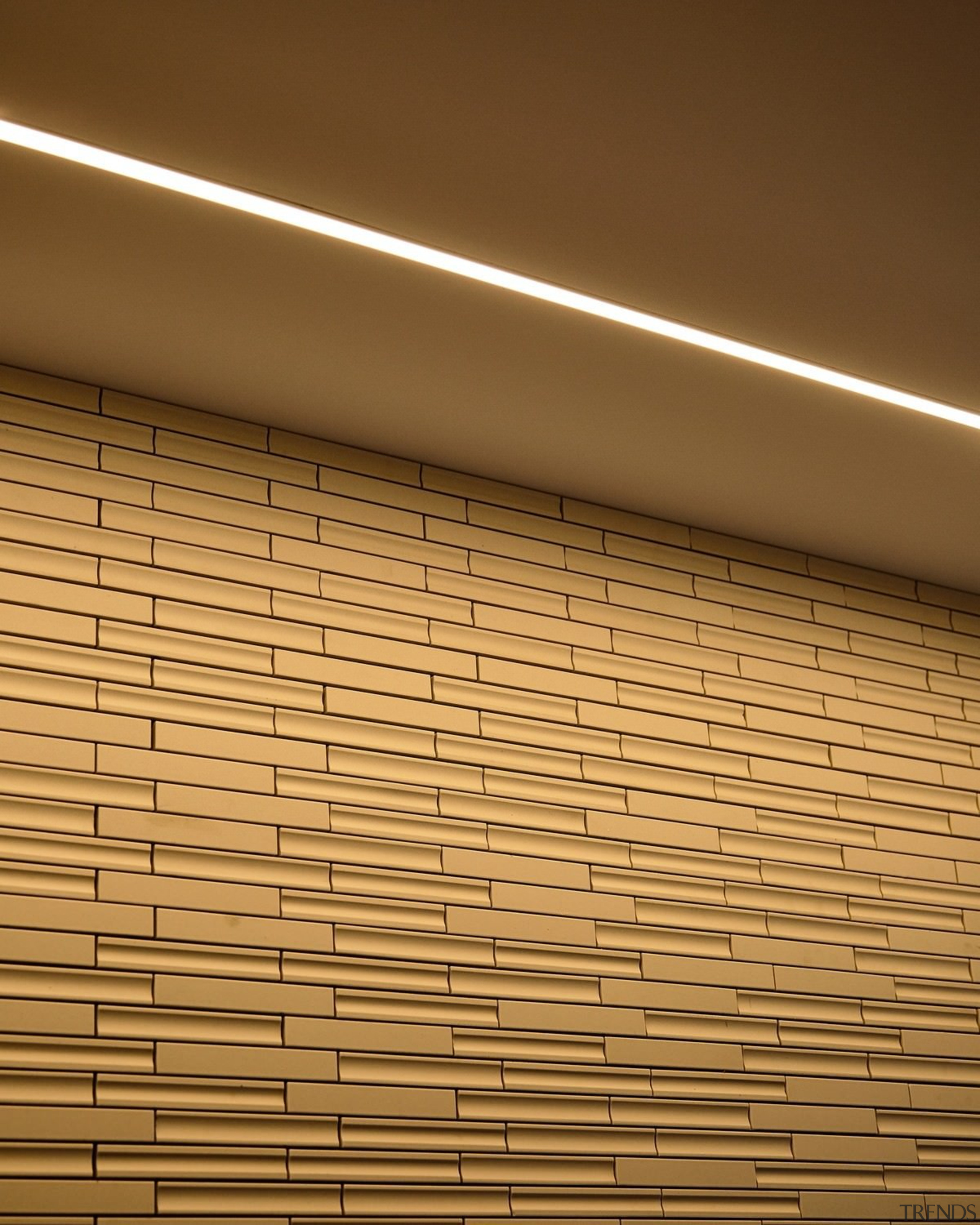 A light strip inset in the ceiling highlights angle, architecture, ceiling, daylighting, floor, light, lighting, line, wall, wood, yellow, brown, orange