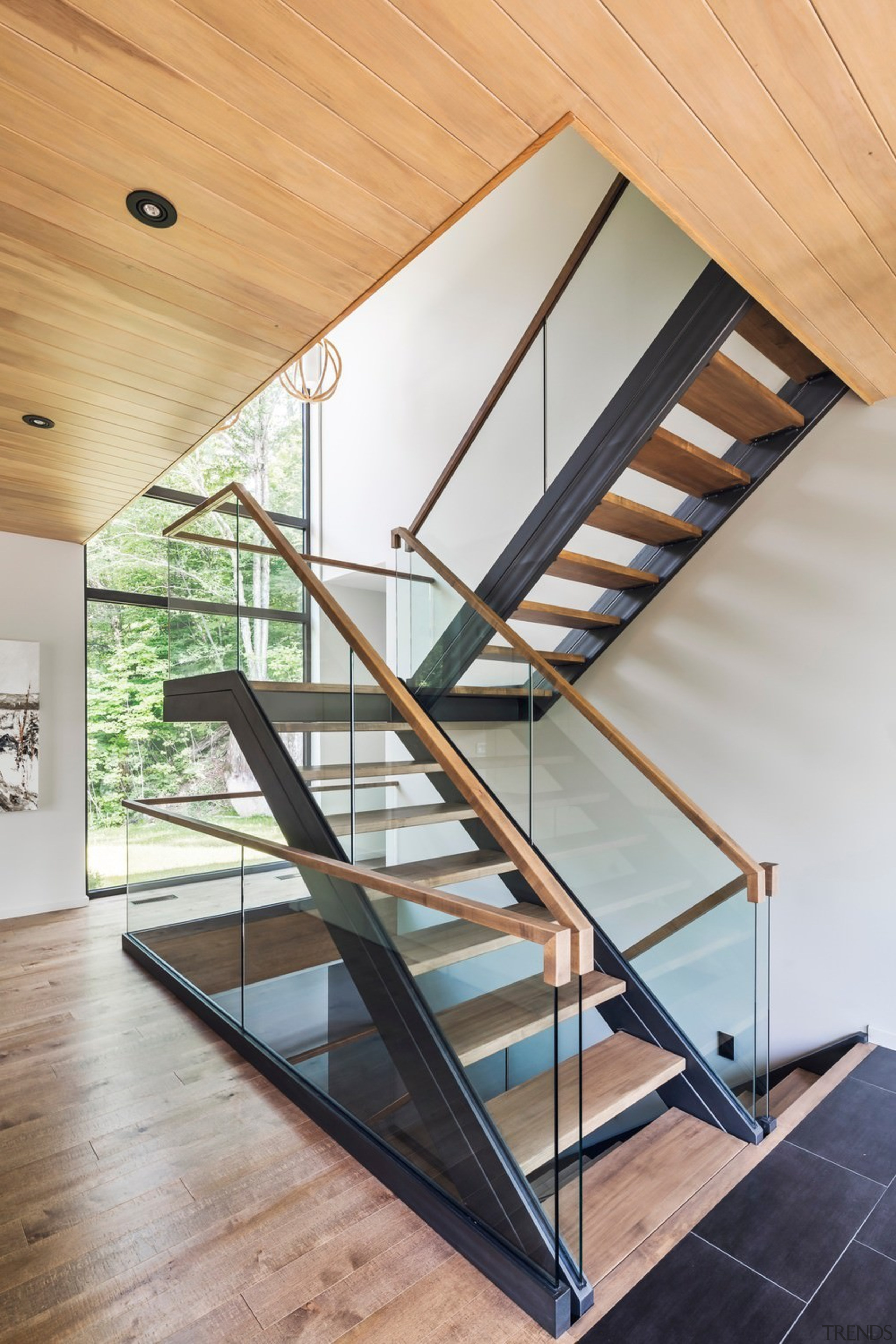 The feature staircase connects all levels of the architecture, daylighting, glass, handrail, house, interior design, product design, stairs, structure, wood, gray, orange