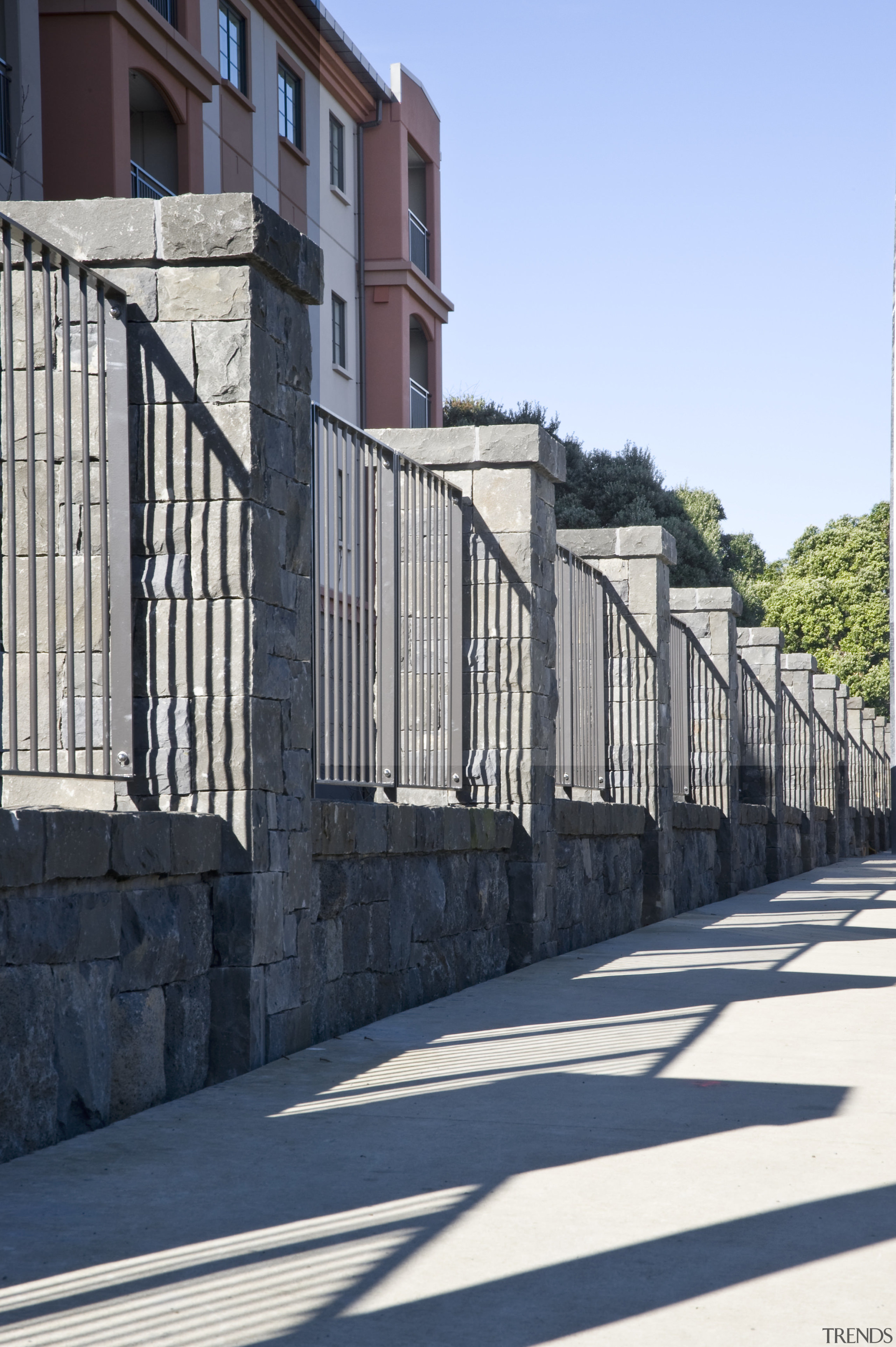 View of the stone wall with metal sections architecture, building, facade, fence, guard rail, handrail, home fencing, house, infrastructure, iron, lane, neighbourhood, outdoor structure, residential area, road, structure, walkway, wall