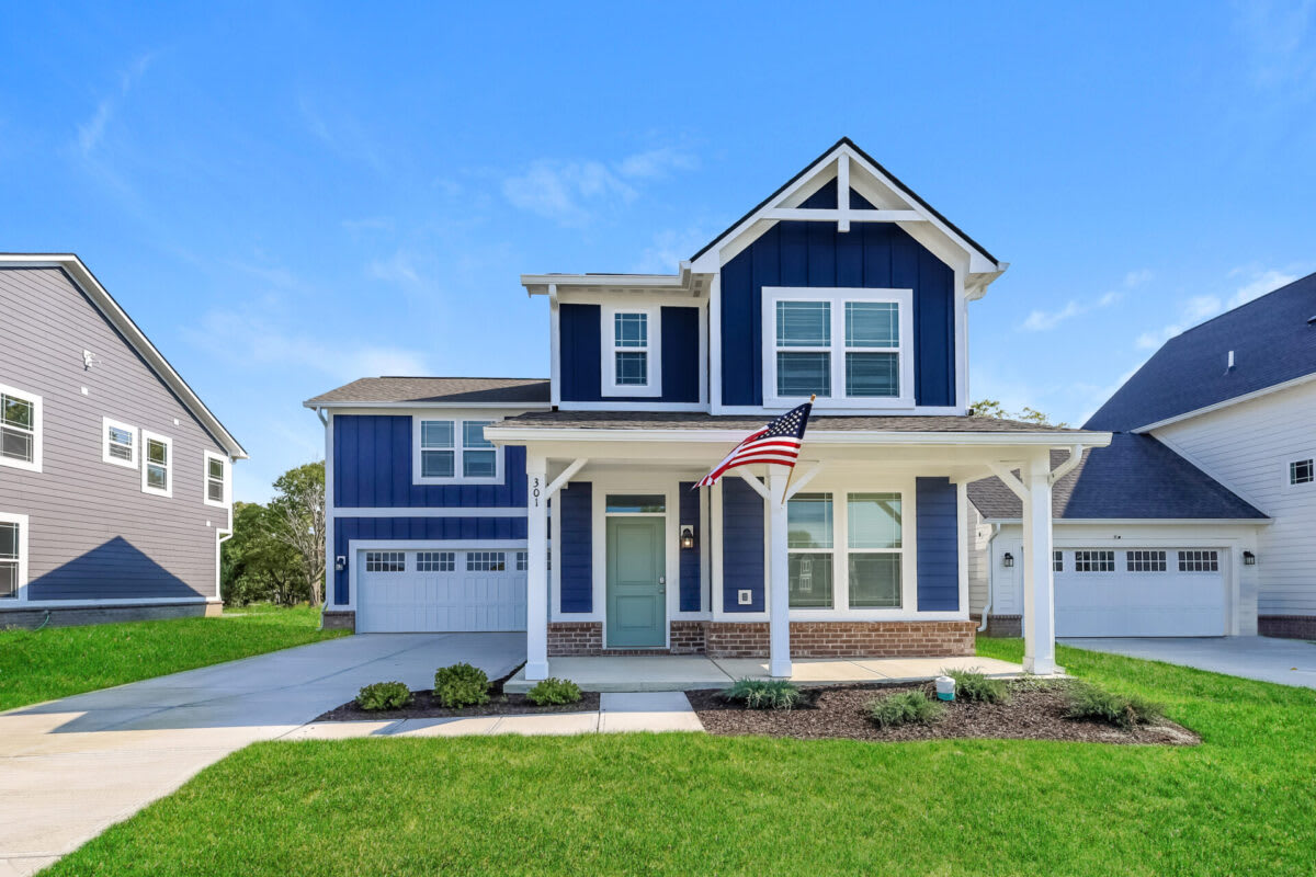 An image of a Tricon home with a blue exterior and an American flag