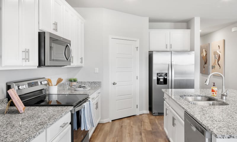 View of kitchen with close-up view of stainless steel appliances such as fridge, microwave, and stove.