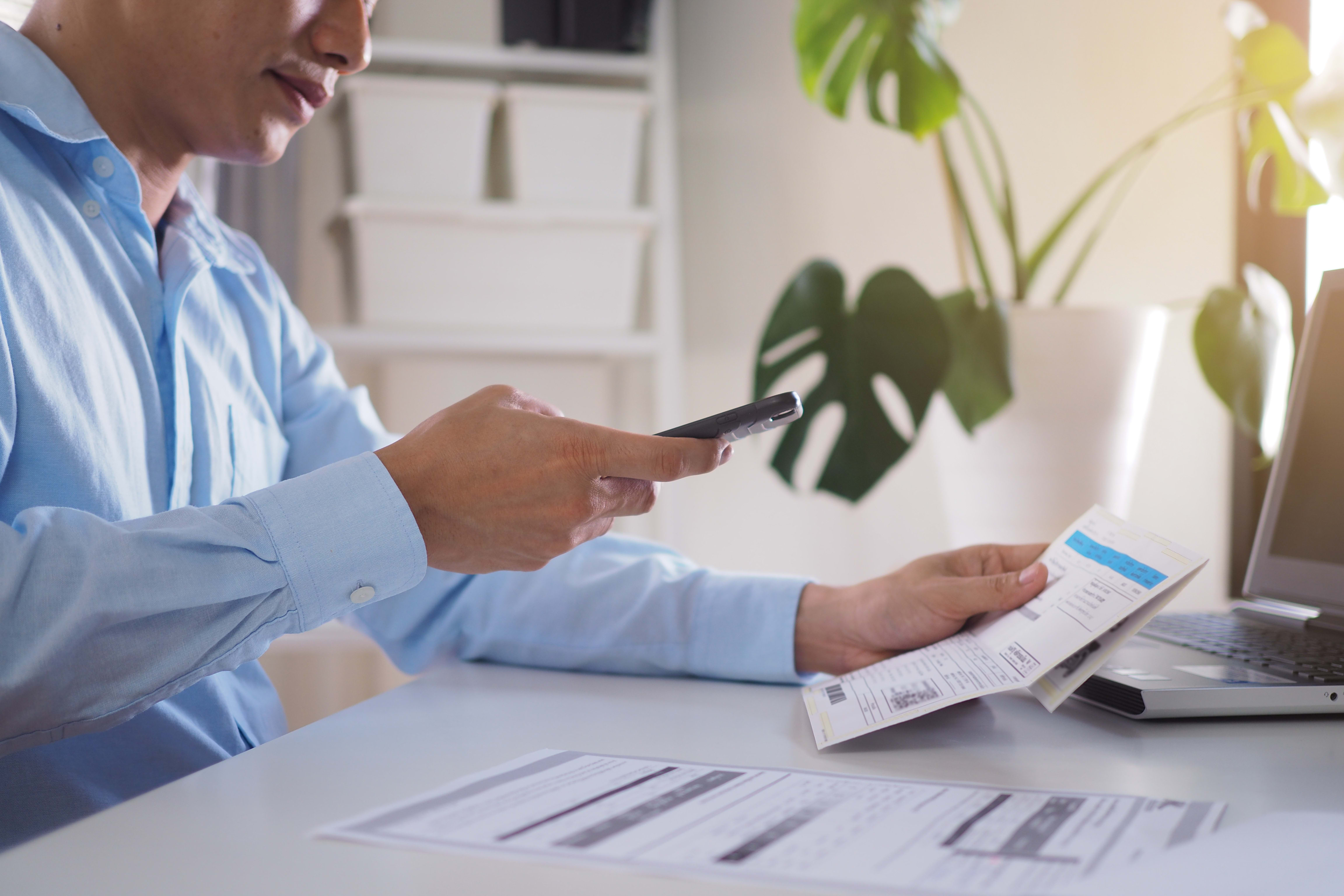 Stock image of man using phone camera to scan receipt for upload