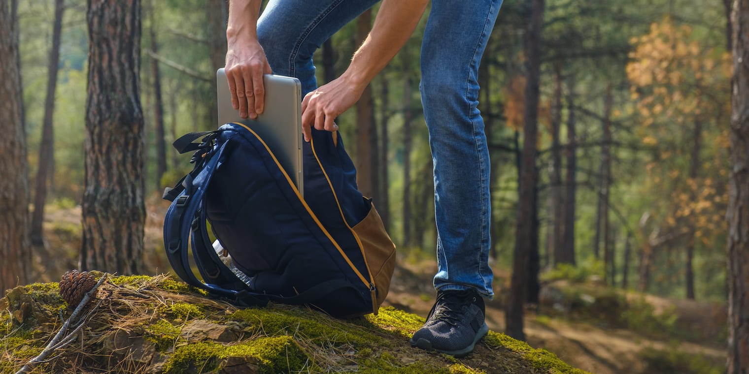 man putting laptop in backpack