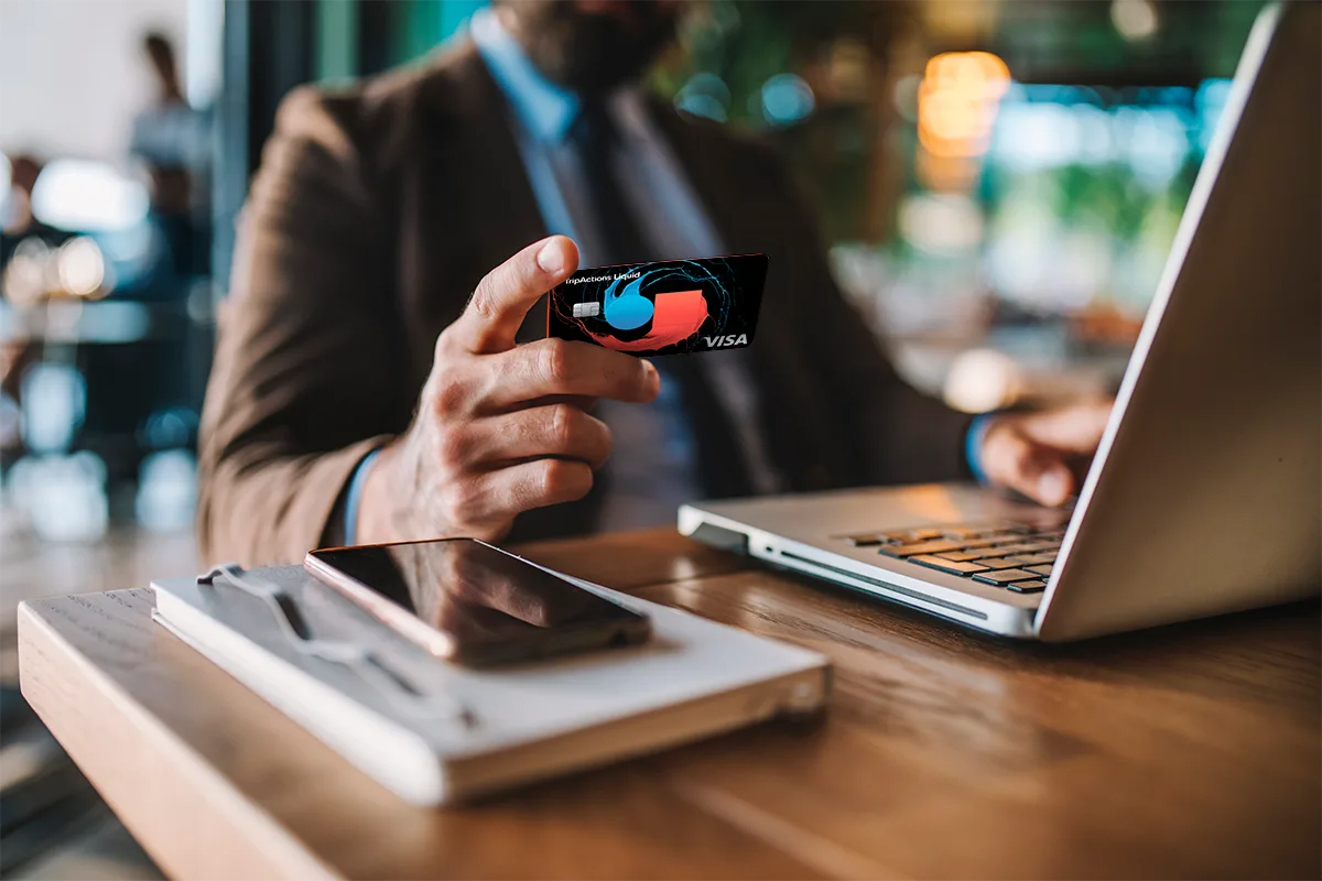 person on a laptop holding TripActions Liquid card