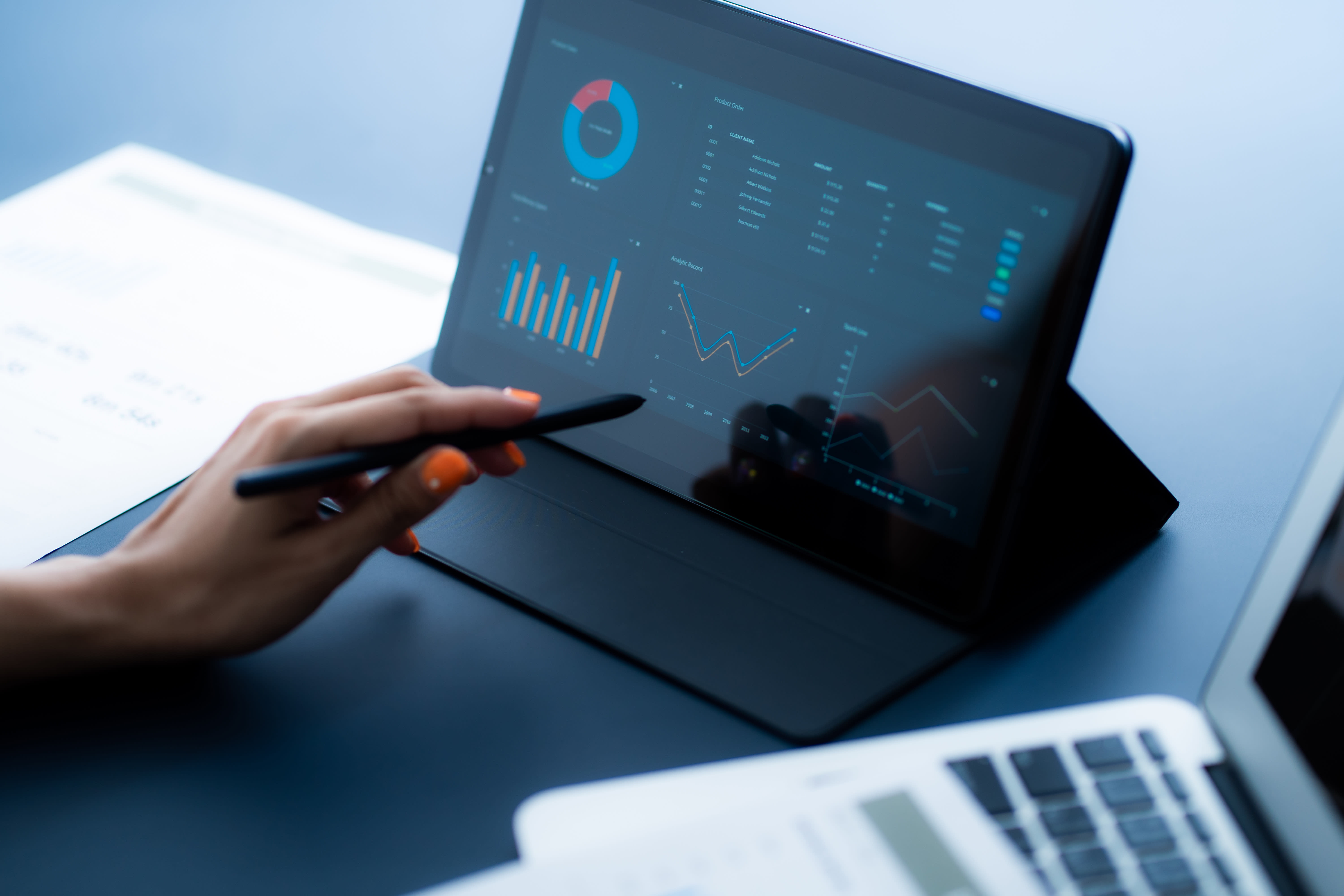 Image of hand with stylus pointing to real-time data charts and graphs on tablet computer